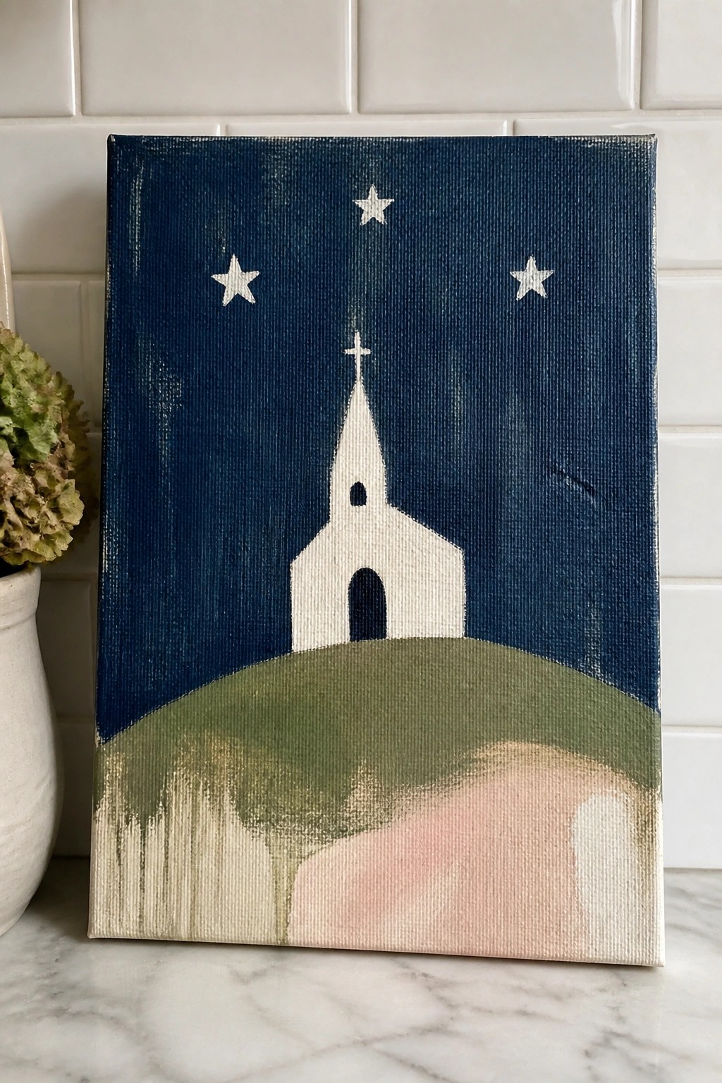 White church steeple on green hill under dark blue sky with three stars