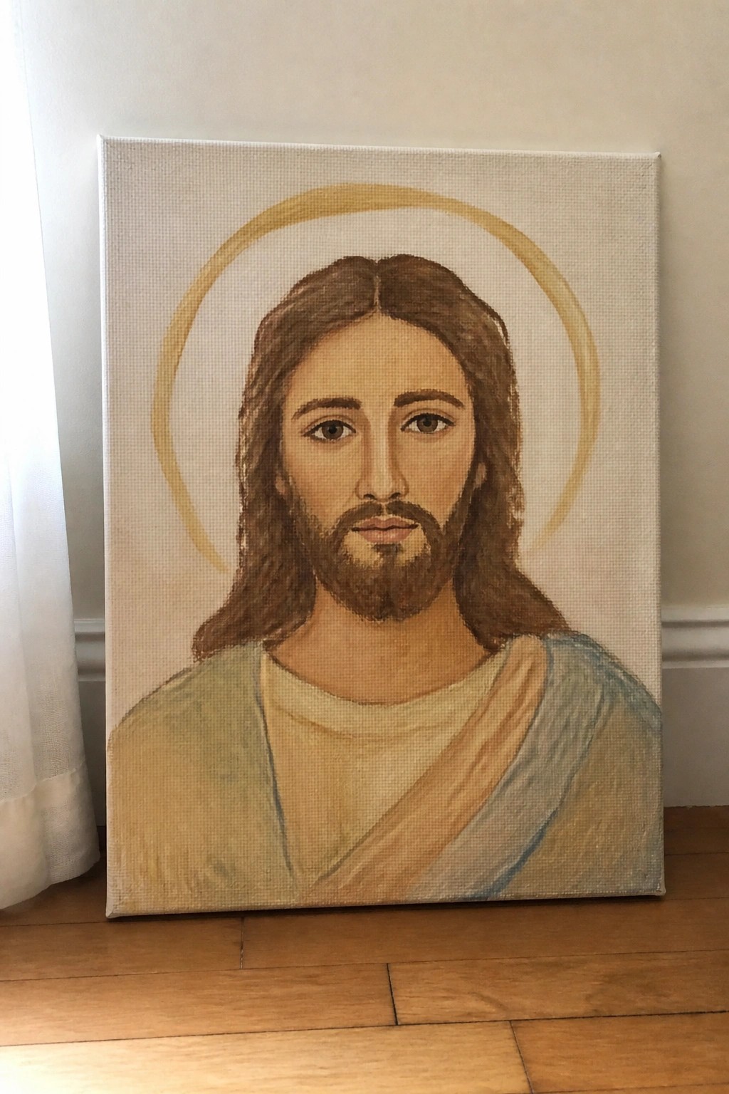 Canvas painting of Jesus with halo and robes propped on wooden floor against wall