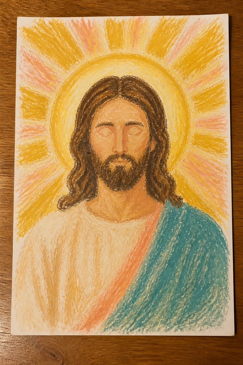 Crayon portrait of Jesus with closed eyes, brown hair, beard, white robe, blue sash, and radiant halo