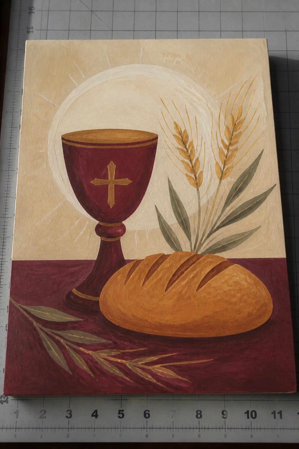 Still life painting of red chalice with cross, bread loaf, and wheat stalks.