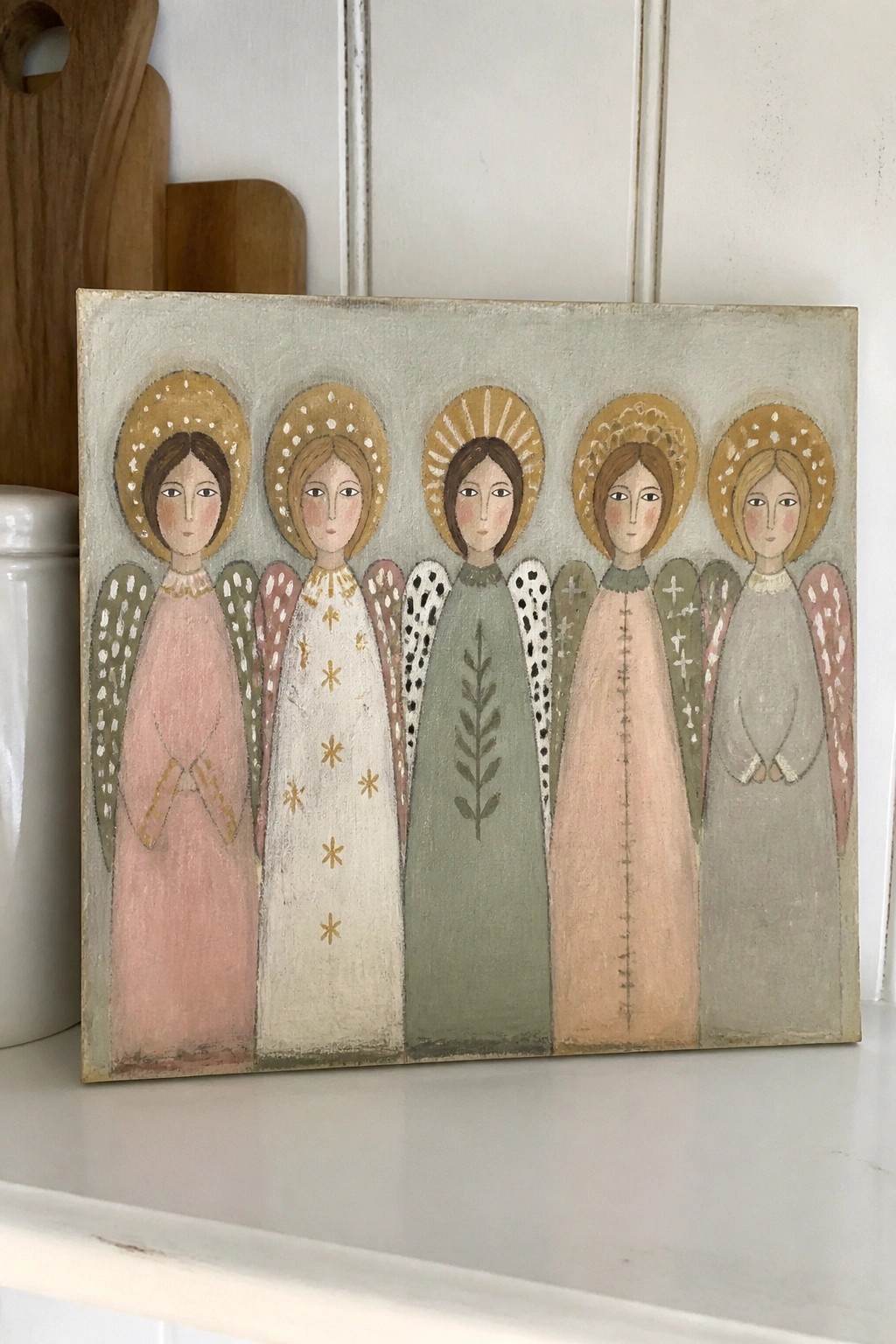 Folk art painting of five angels in pink, white, green, peach, and gray robes with halos
