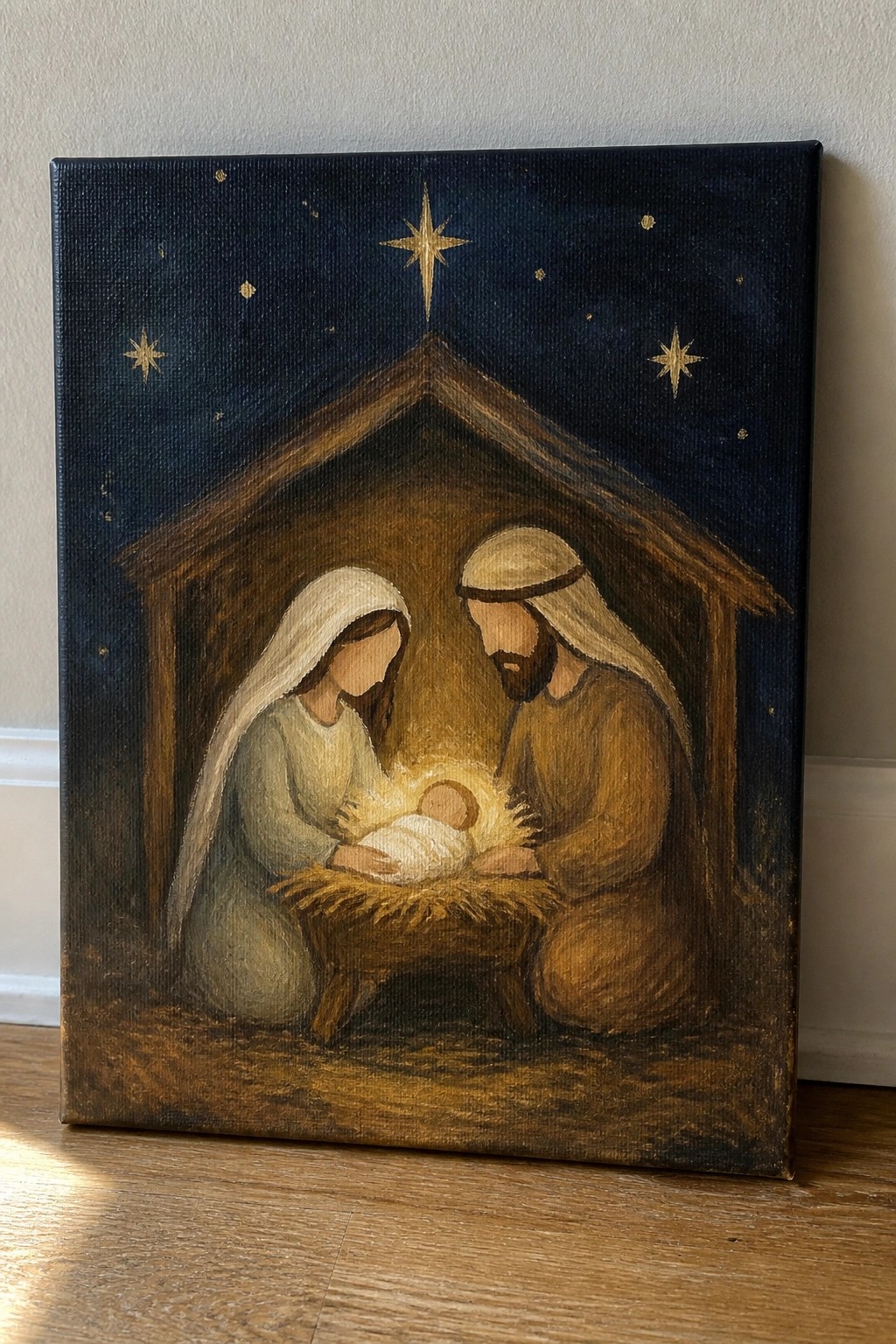 Nativity painting of Mary in white veil, Joseph in brown robe, and infant in manger under stars.