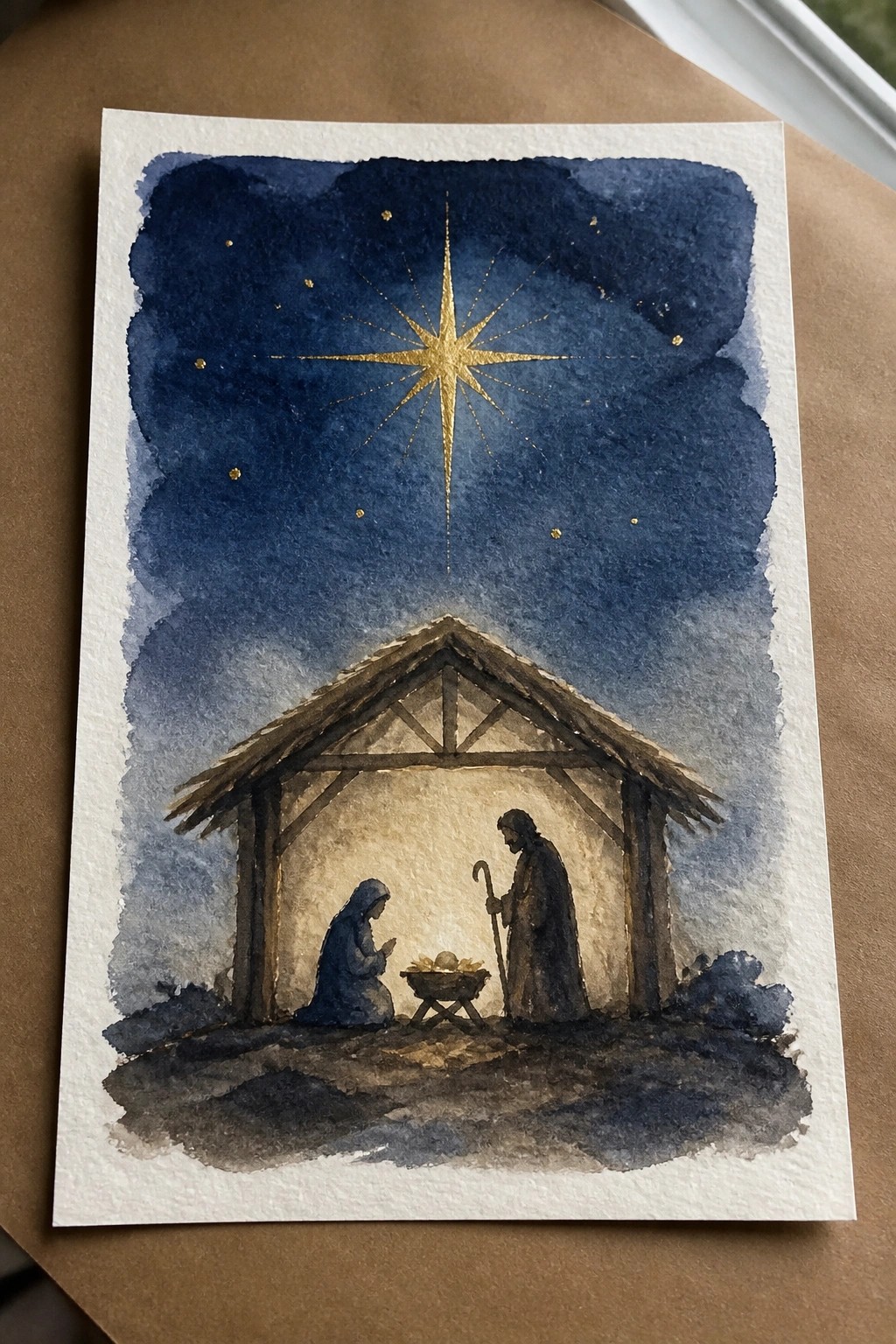 Watercolor nativity: Mary in blue kneels by manger, Joseph with staff under golden star.