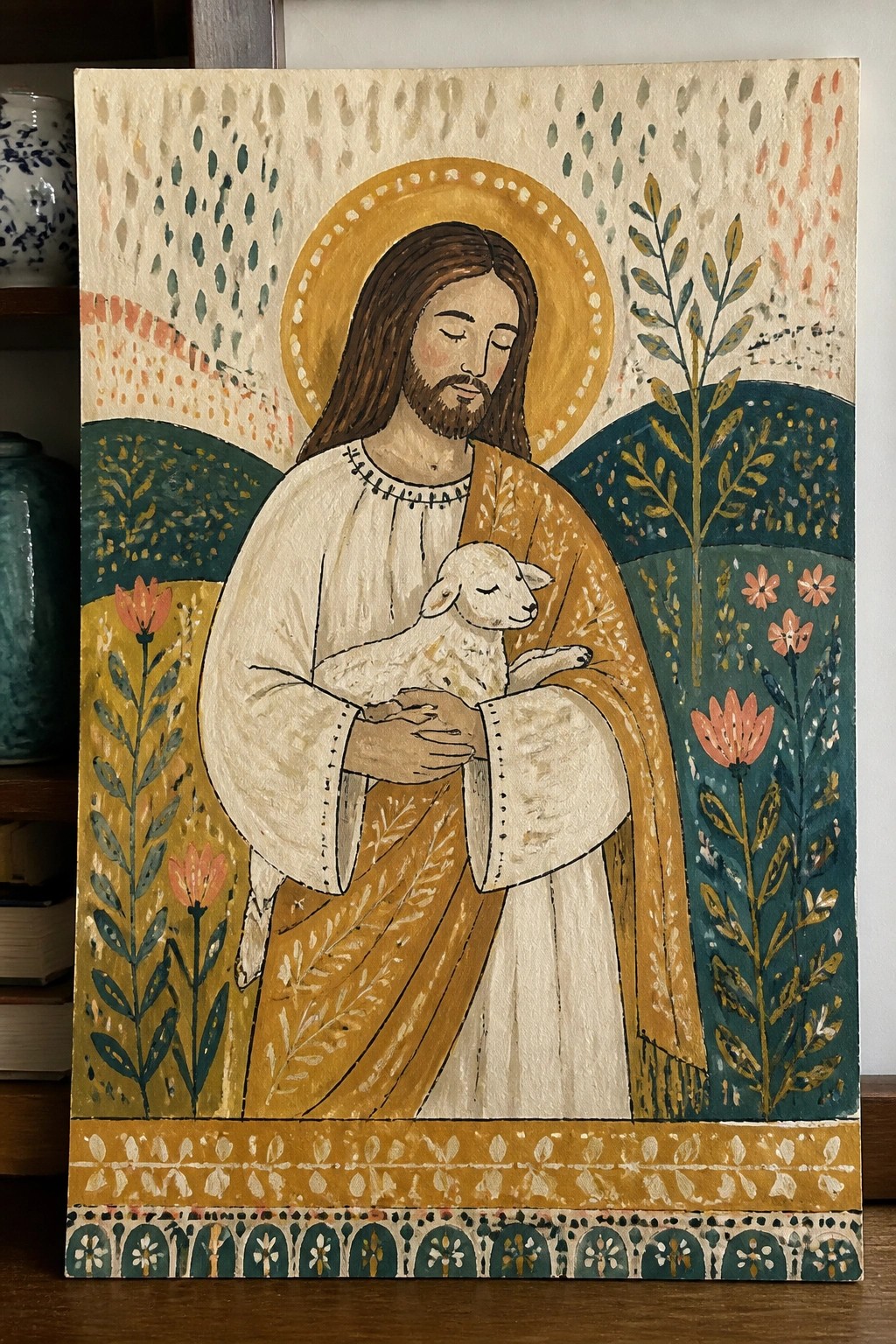 Folk-style painting of robed Jesus with halo cradling a lamb amid colorful plants.