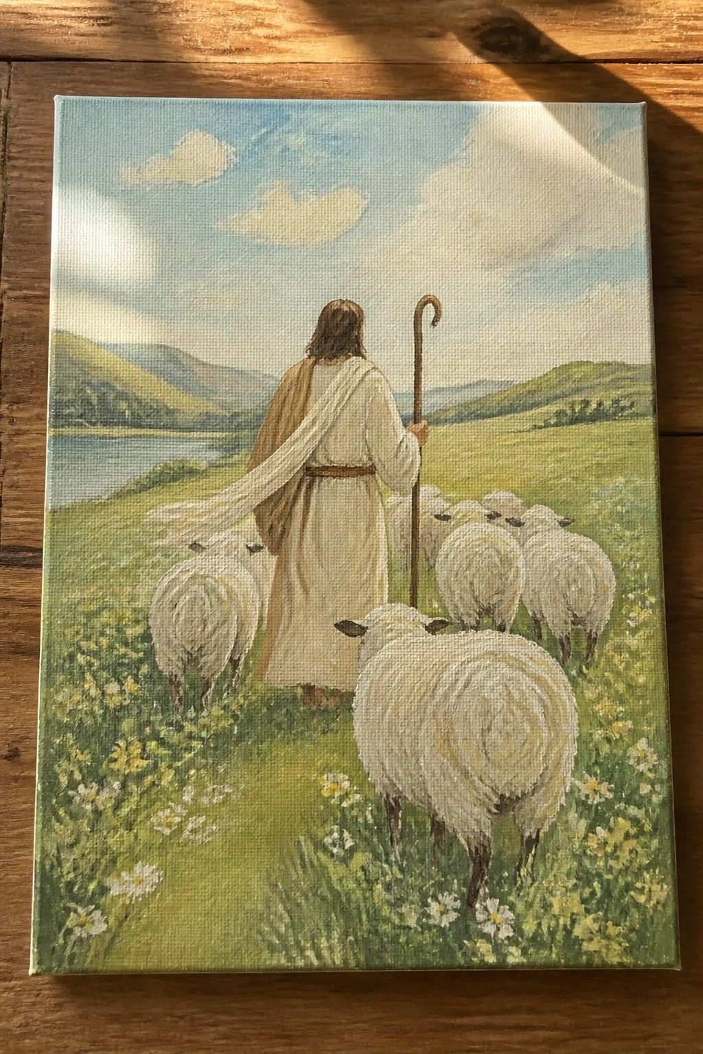 Robed shepherd with staff leads flock through flower-filled green meadow by lake and hills