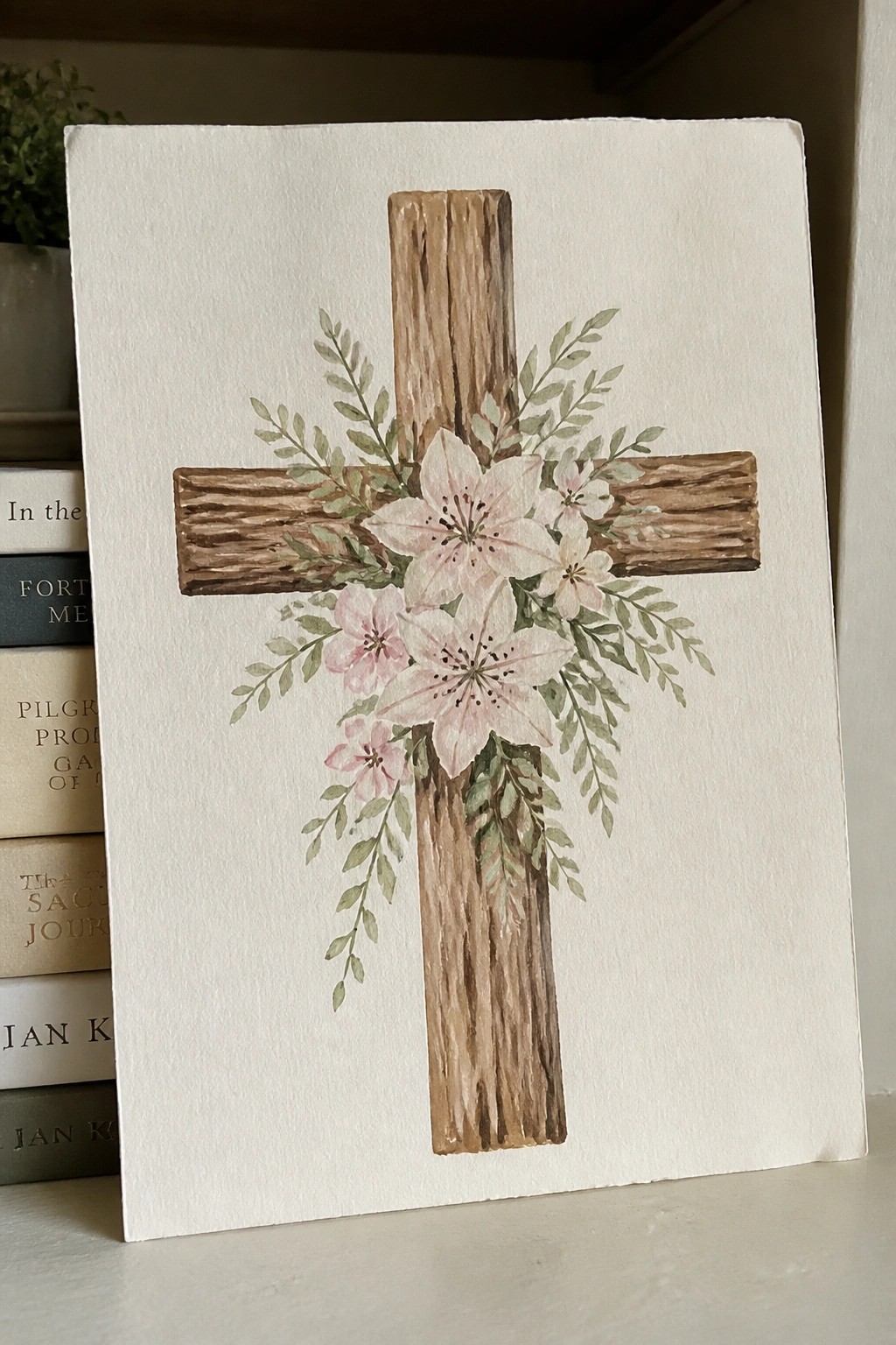 Watercolor painting of rustic wooden cross with pink lilies and green foliage on paper.