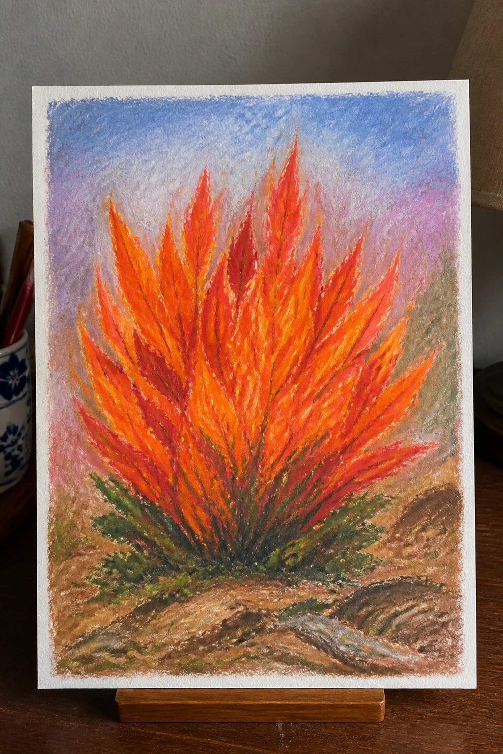 Vibrant orange-red flame-like plant in pastel landscape with blue-purple sky and rocks