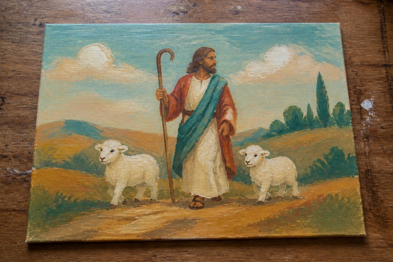 Bearded shepherd in white robe with blue sash holds staff beside two white lambs in landscape.