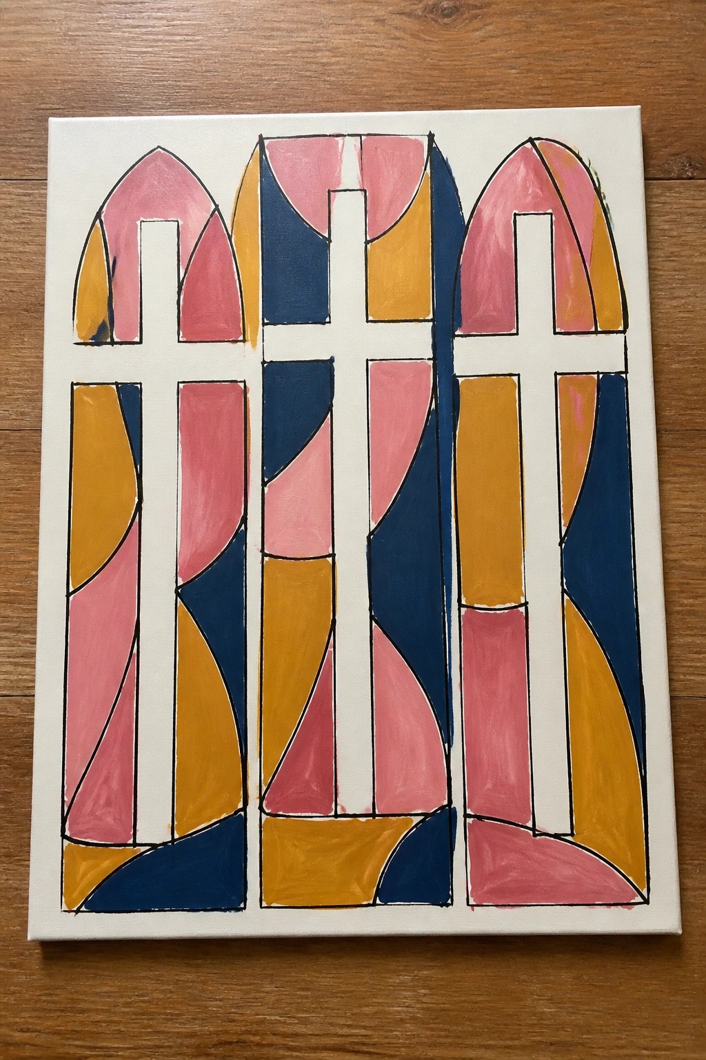 Abstract painting of three arched crosses in pink, yellow, and navy blue.