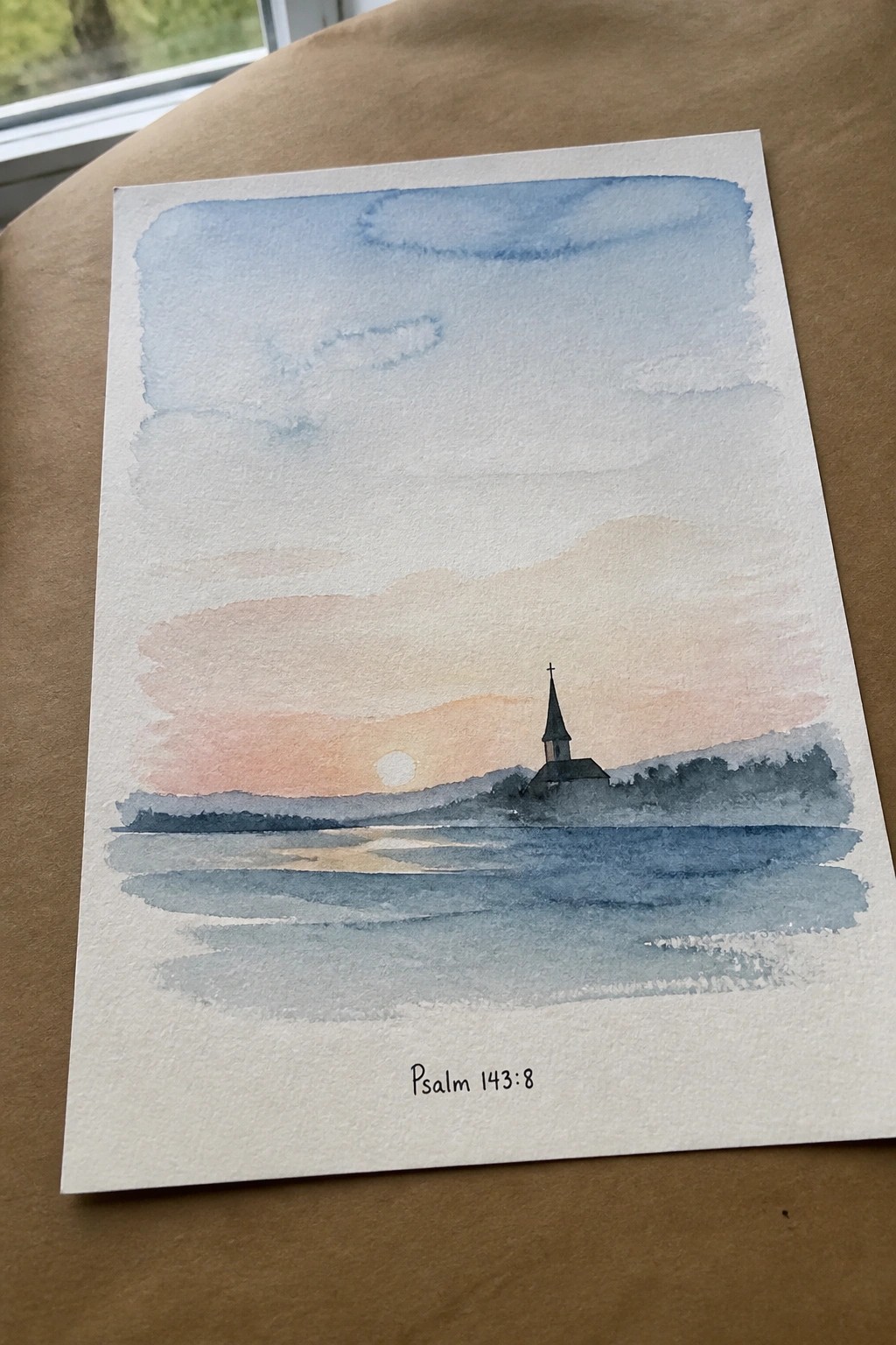 Watercolor sunset over water with church steeple, hills, and Psalm 143:8 text below