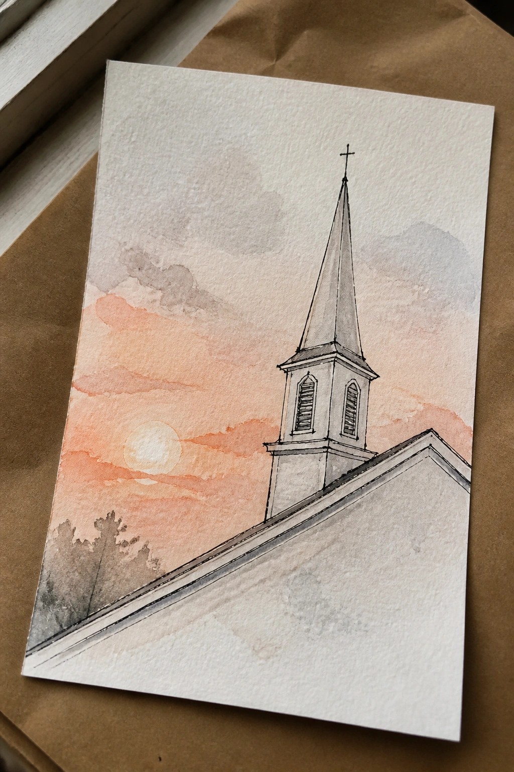 A watercolor painting of a church steeple with a cross against an orange sunset sky with a low sun and soft clouds.