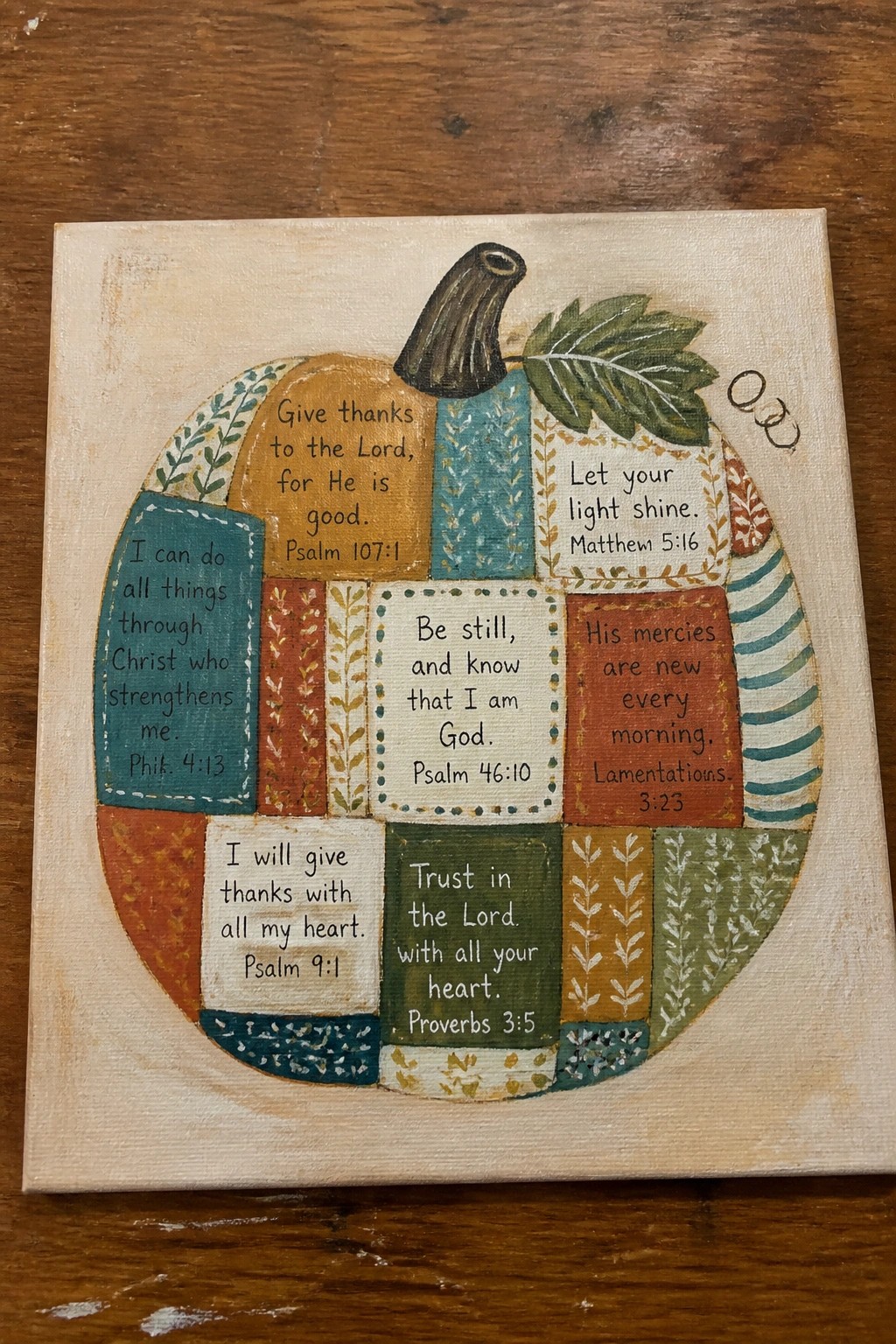 Colorful patchwork pumpkin canvas art with Bible verses, stem, and leaf on wood.