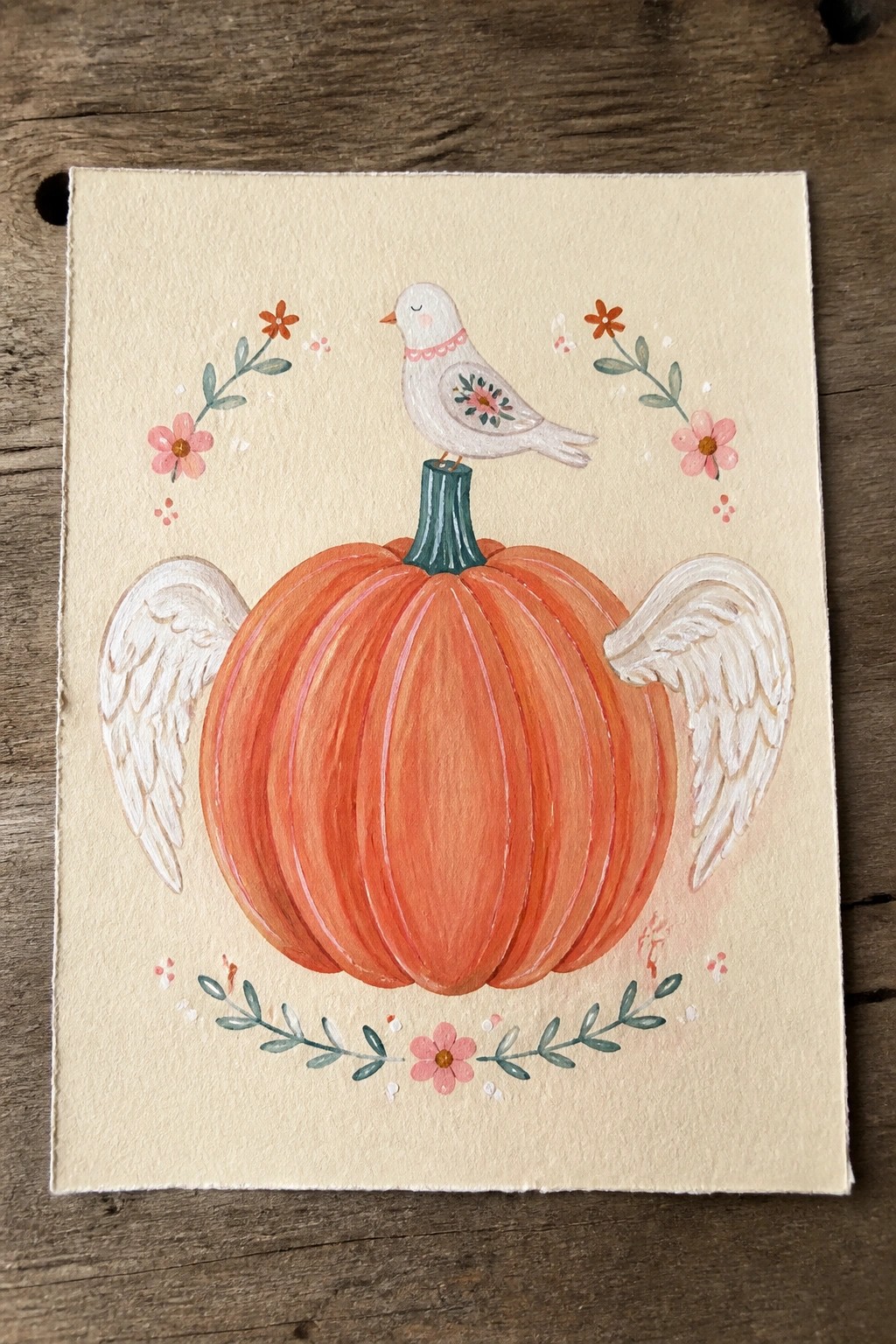Watercolor of winged orange pumpkin with bird on stem amid pink flowers and leaves