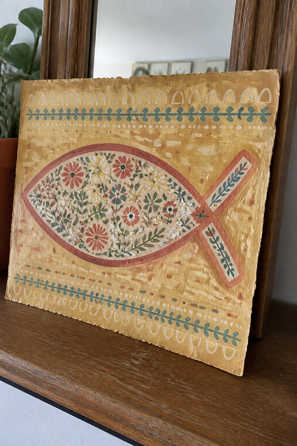 Painted fish with colorful florals and overlapping cross on textured yellow background