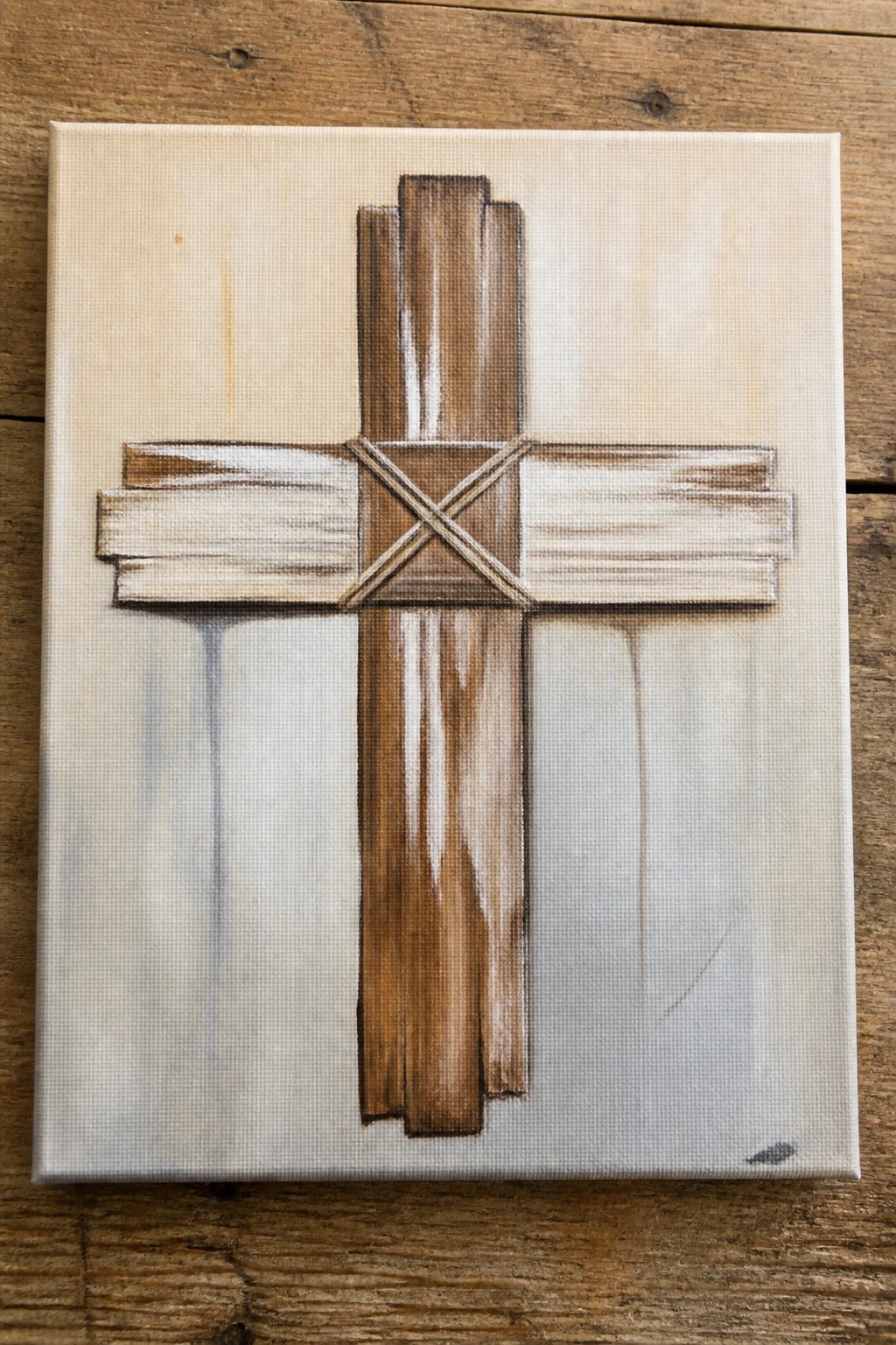 Rustic wooden cross with rope ties on a textured beige canvas.