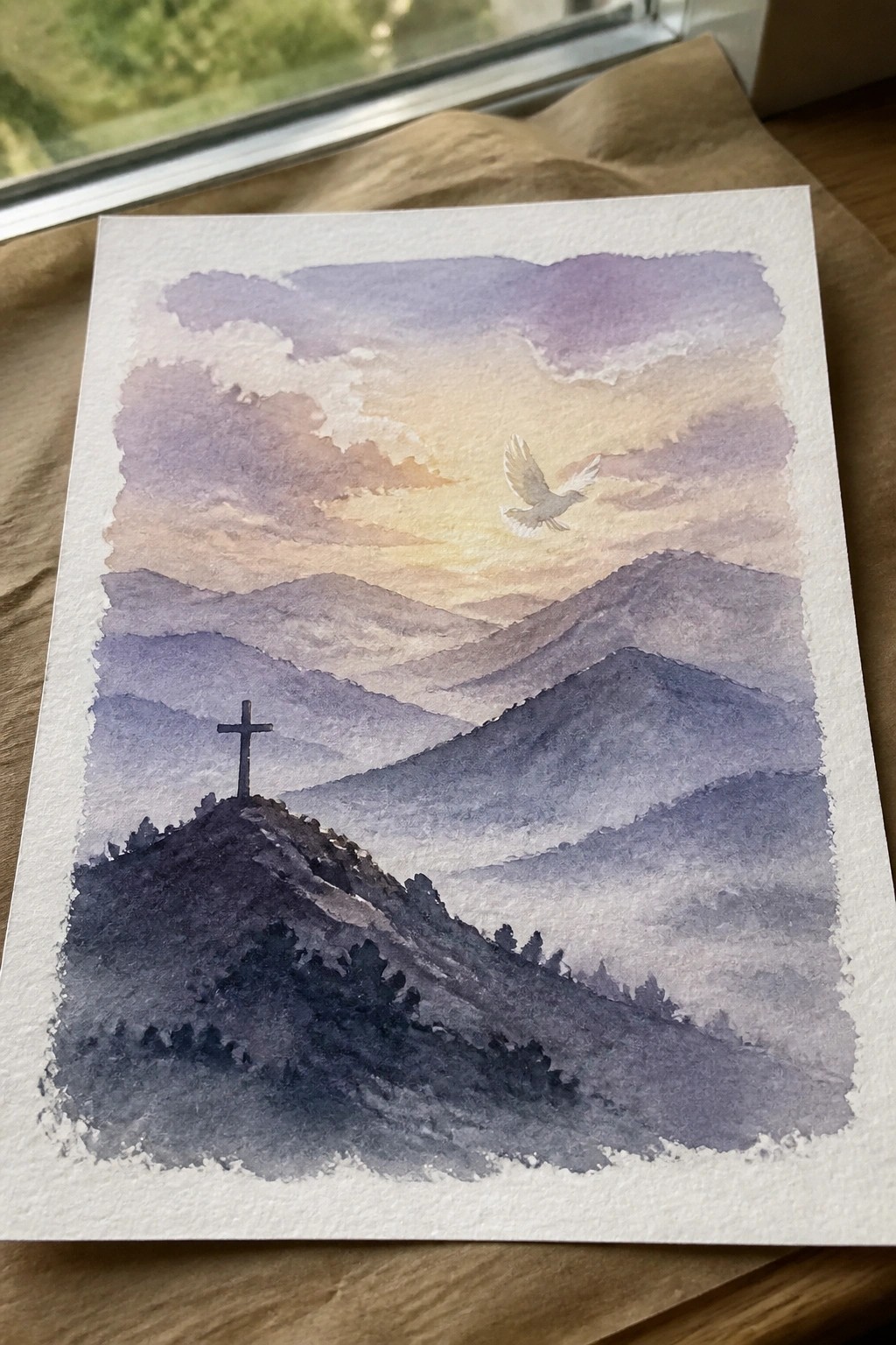 A watercolor landscape painting showing layered mountains, a cross on a hill, and a white dove in a colorful sky.
