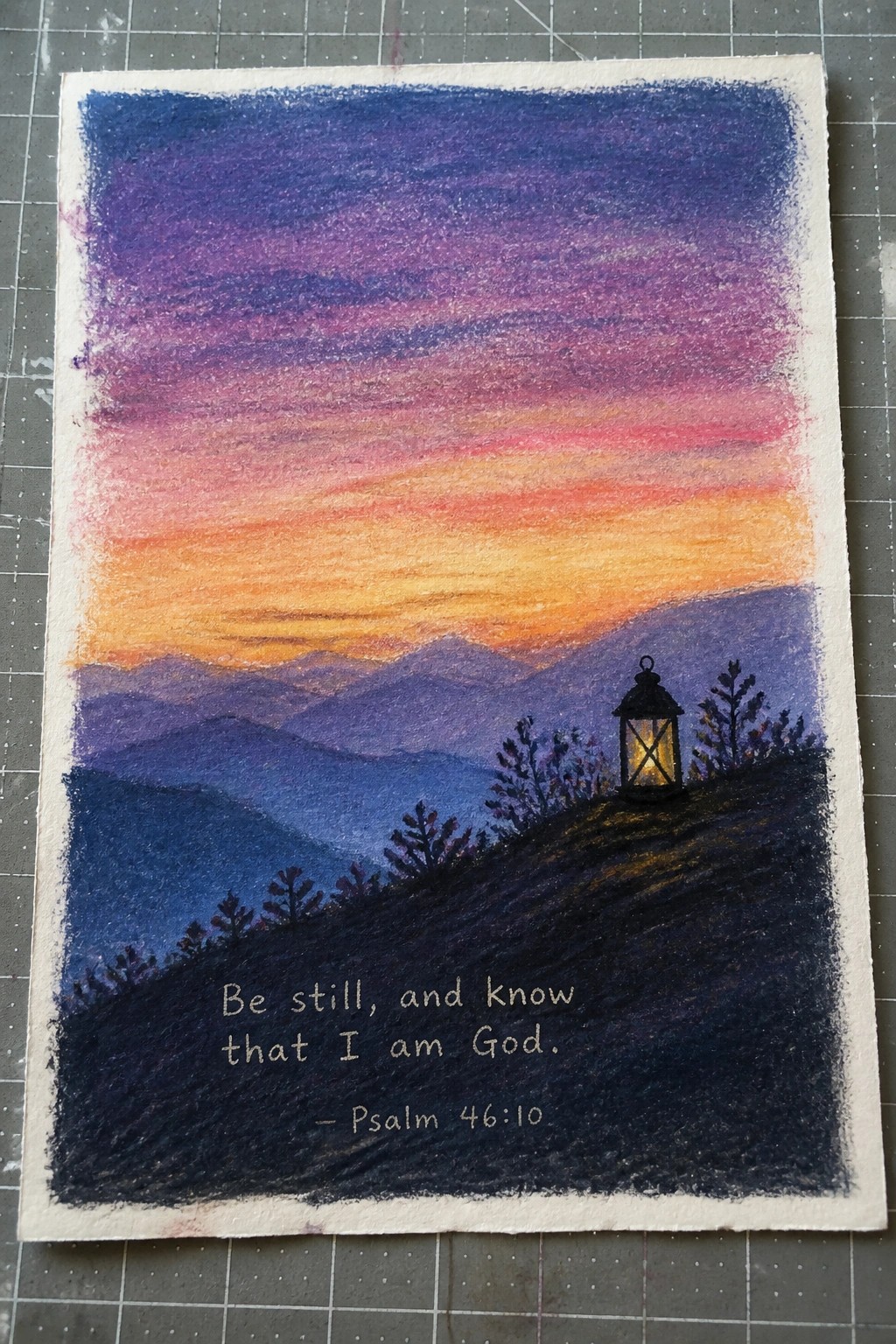 Colorful sunset over silhouetted mountains with glowing lantern and Psalm 46:10 text