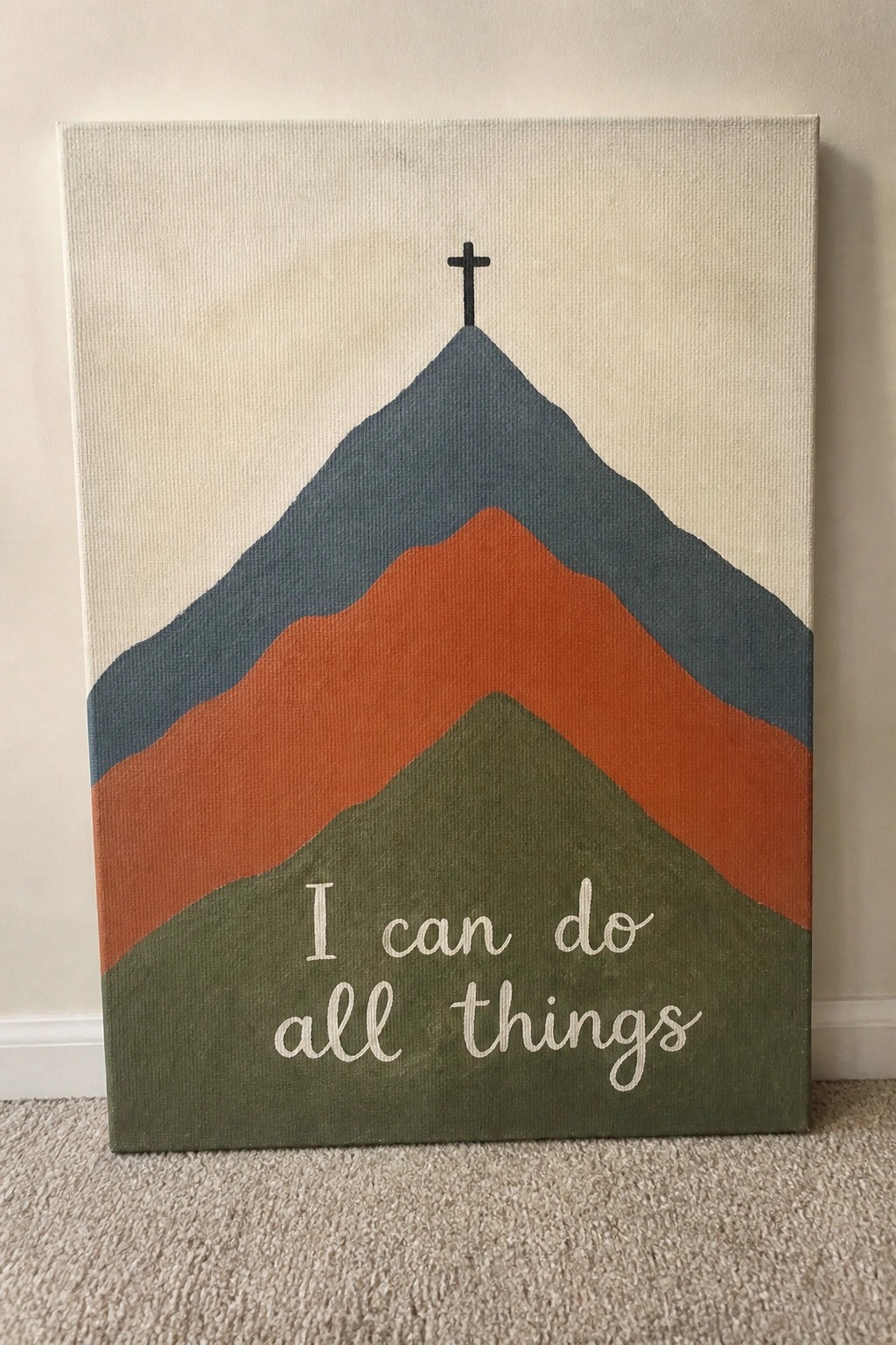 Layered mountains in blue, orange, and green with black cross and white cursive text