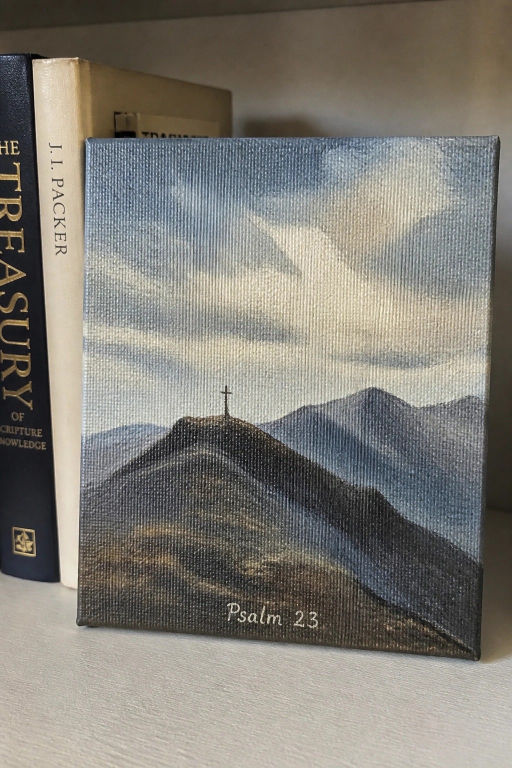 Canvas art of cross on hill labeled Psalm 23 leaning against books