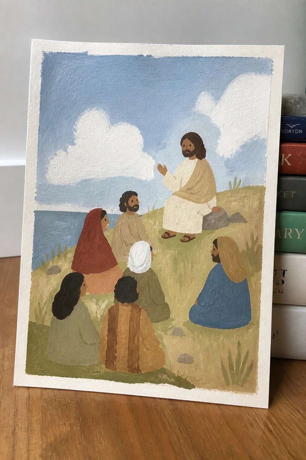 Jesus in white robes gestures to followers in colorful attire on seaside hill