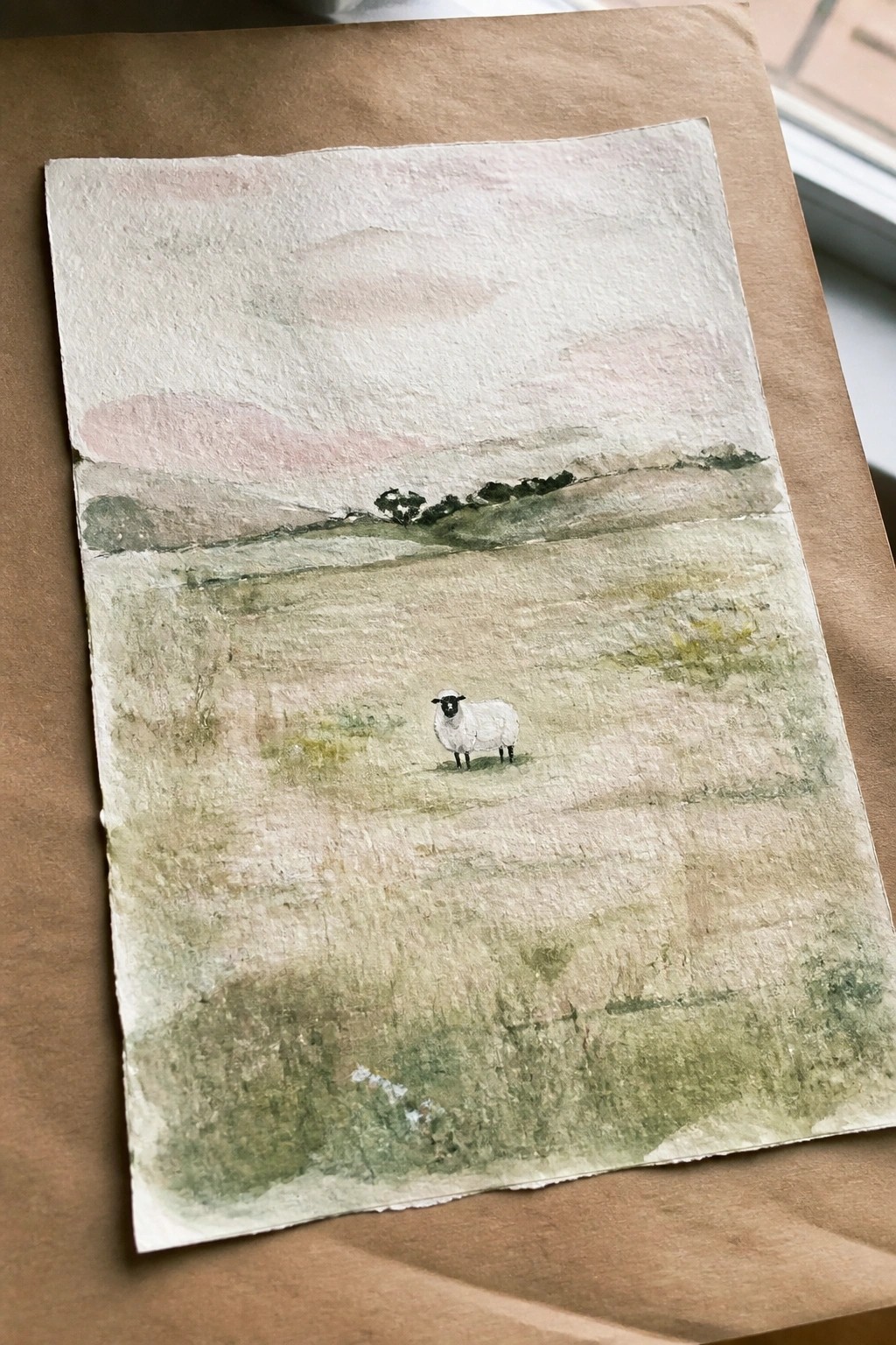 A watercolor painting of a single white sheep standing in a green field with rolling hills and a pale sky above.