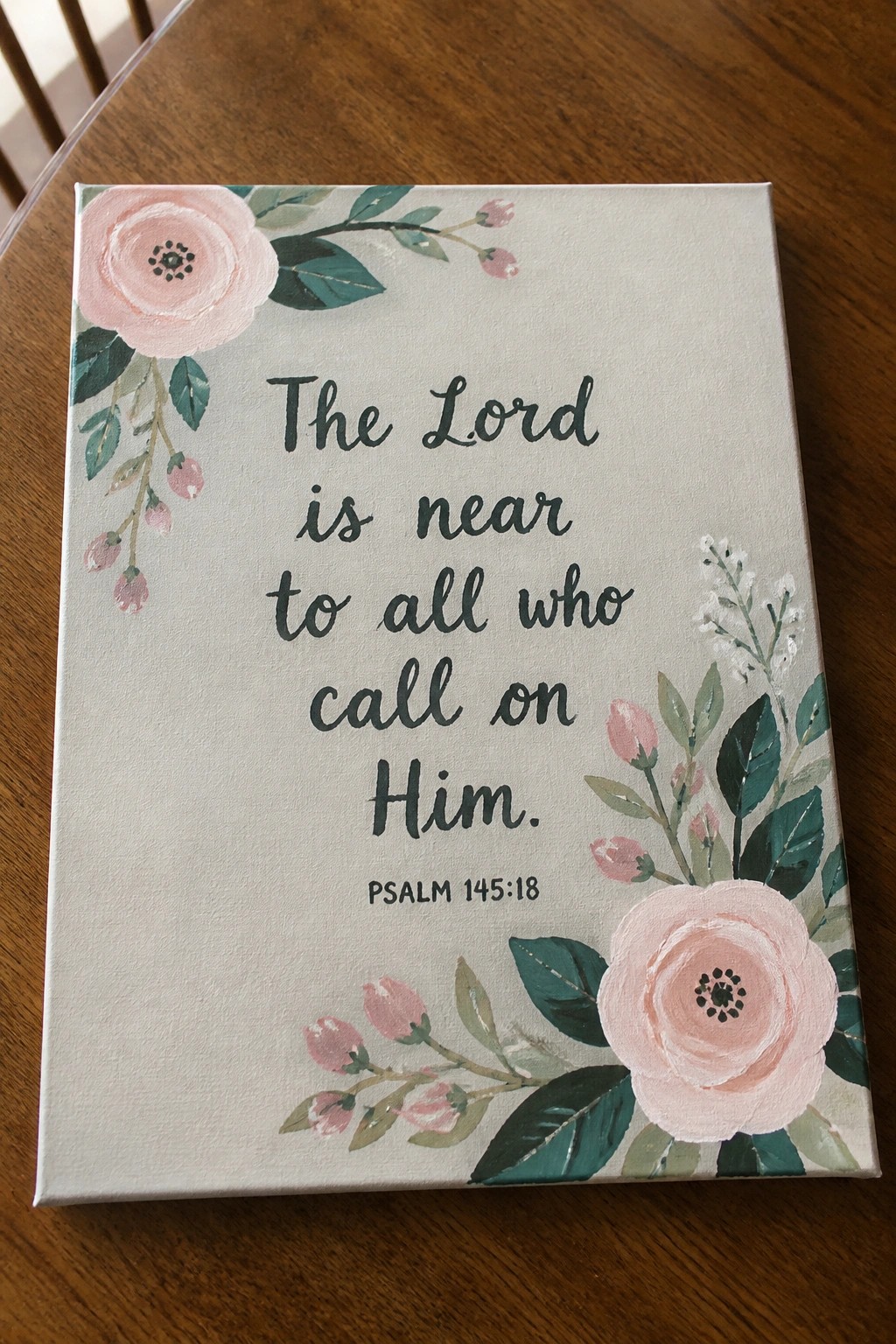 Canvas with pink flowers and Psalm 145:18 verse on wooden table