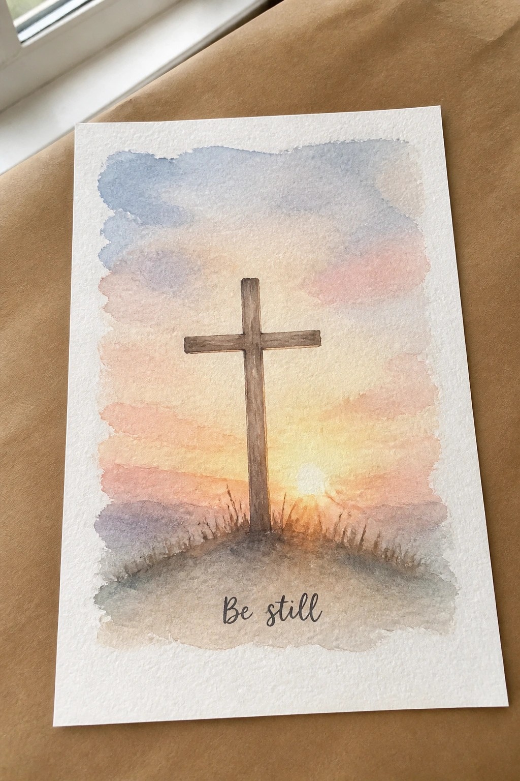 Watercolor painting of wooden cross on hill at sunset with 