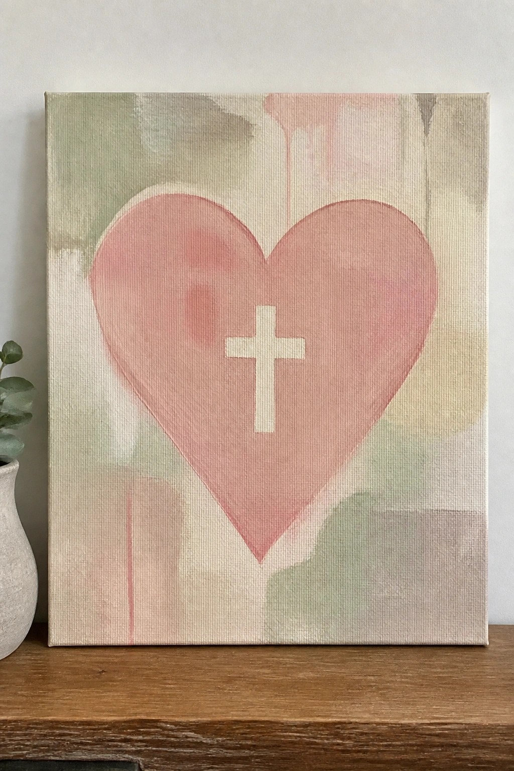 Pink heart with white cross on canvas with soft abstract pastel background on wood shelf
