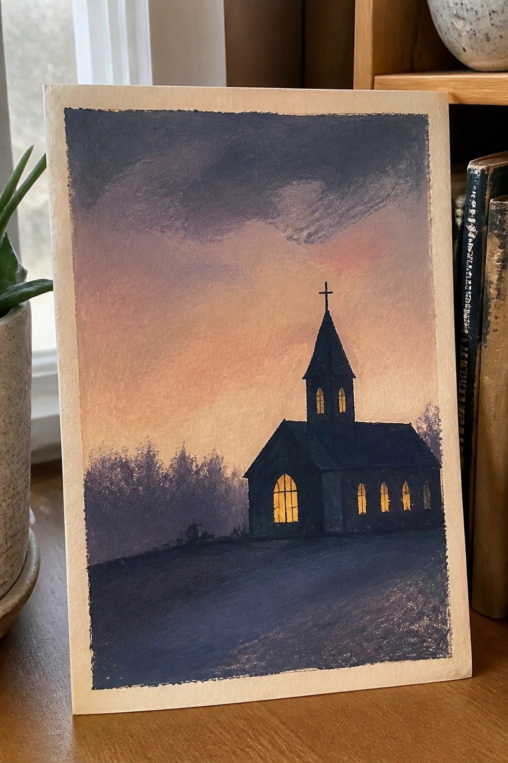 Watercolor painting of silhouetted church with glowing windows under purple-orange sunset sky