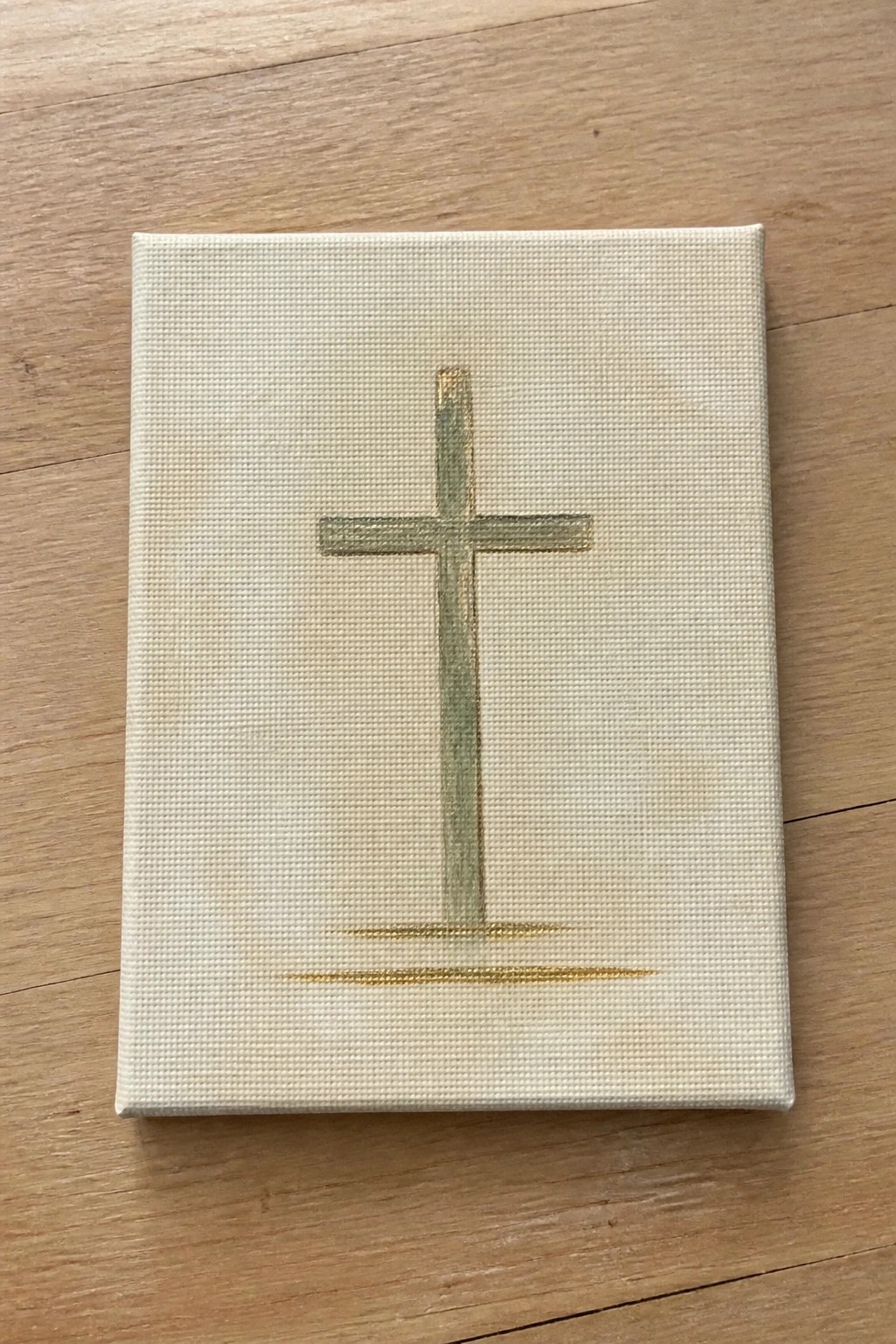 Off-white canvas with muted green-gold cross and base lines on wood.