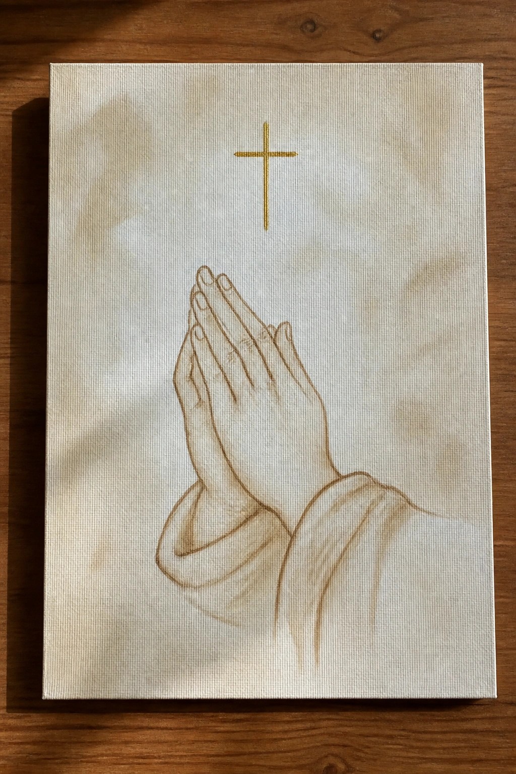 Praying hands in white robe beneath golden cross on beige canvas