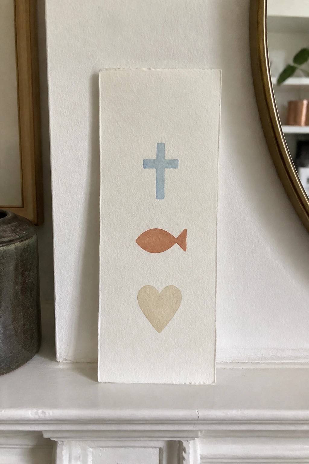 White card with blue cross, orange fish, and beige heart symbols displayed vertically