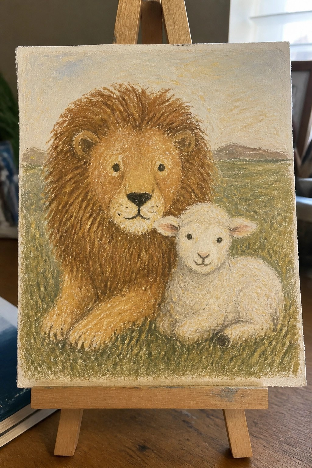 Pastel painting on easel of lion with brown mane beside white lamb in field.