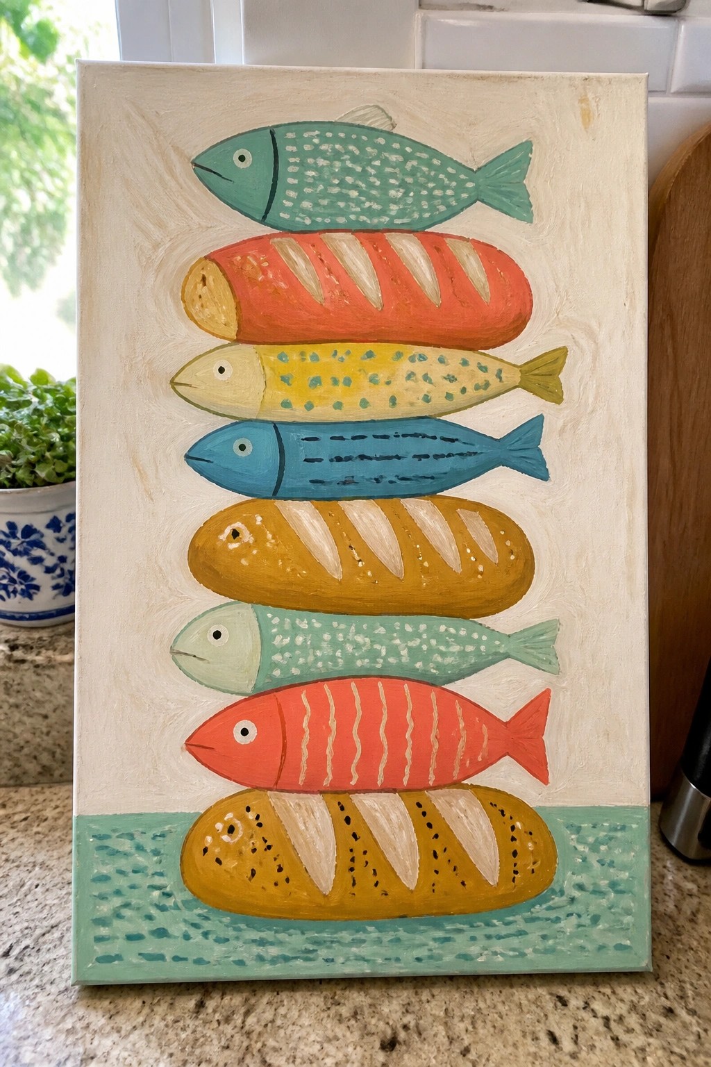 Whimsical painting of stacked colorful fish and baguettes on white canvas with green base
