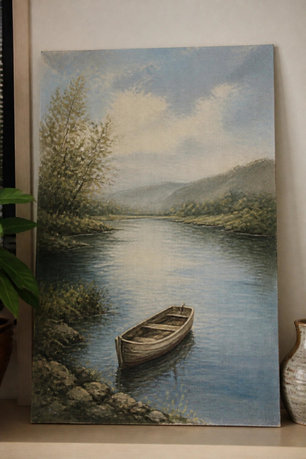 Realistic painting of rowboat on calm river with trees, hills, and cloudy sky.
