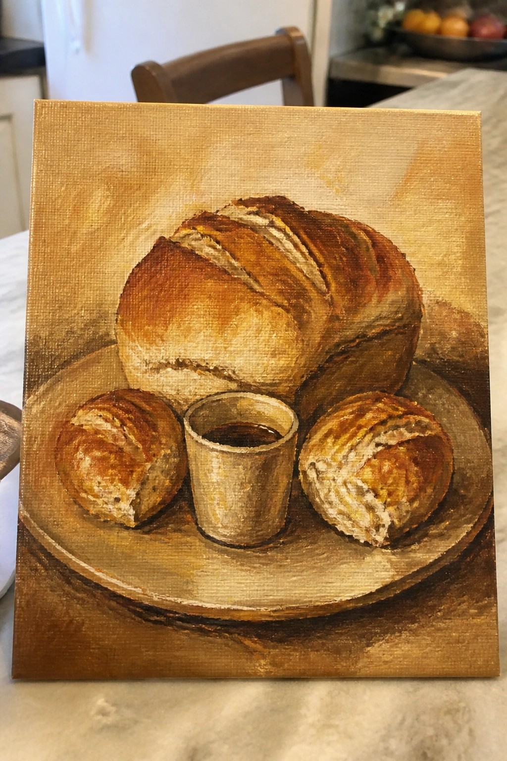 Still-life painting of crusty bread loaf, rolls, and cup on golden plate