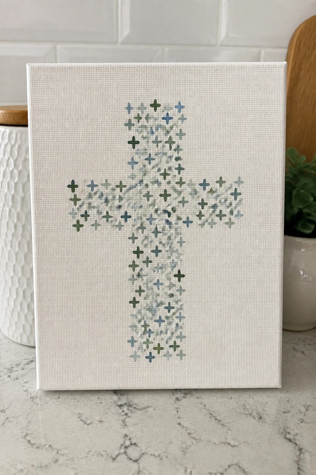Canvas with cross of small blue and green plus signs on marble counter
