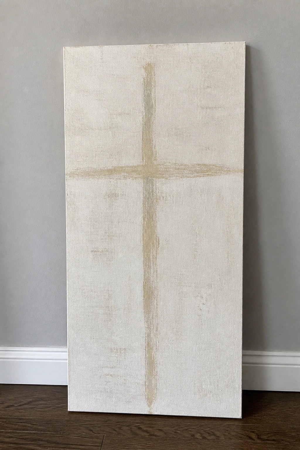 Minimalist canvas with faint beige cross on textured off-white background against gray wall