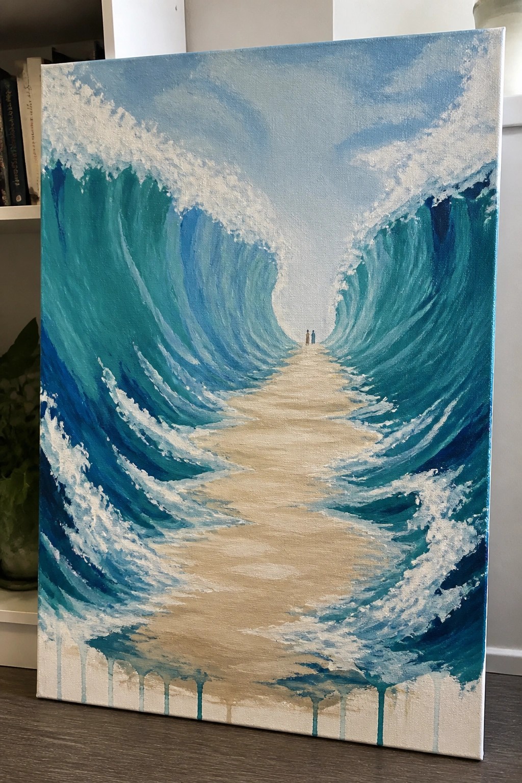Towering blue waves curve over a sandy path toward two distant figures.