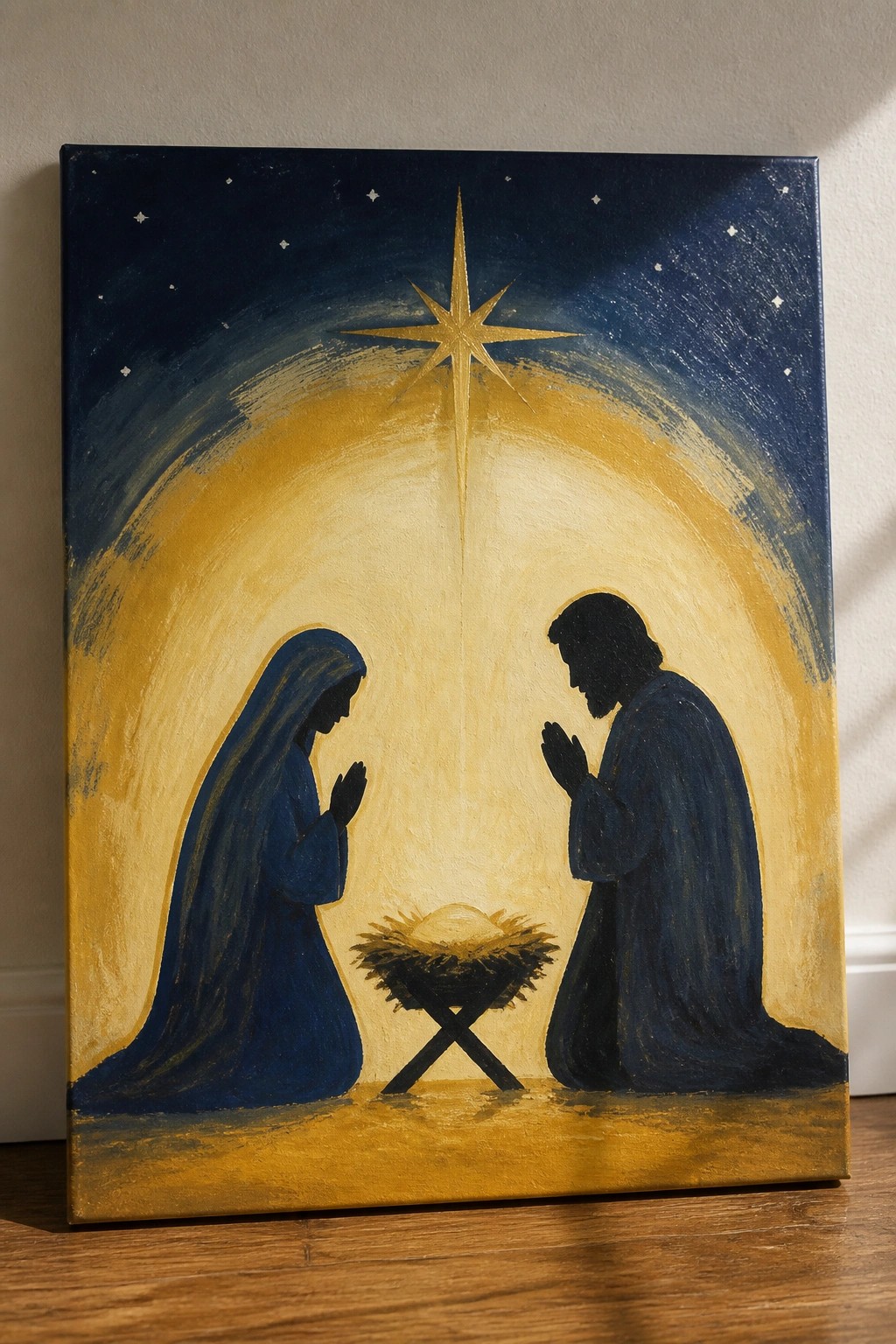 Blue-robed Mary and Joseph kneel praying beside manger under golden star in painting