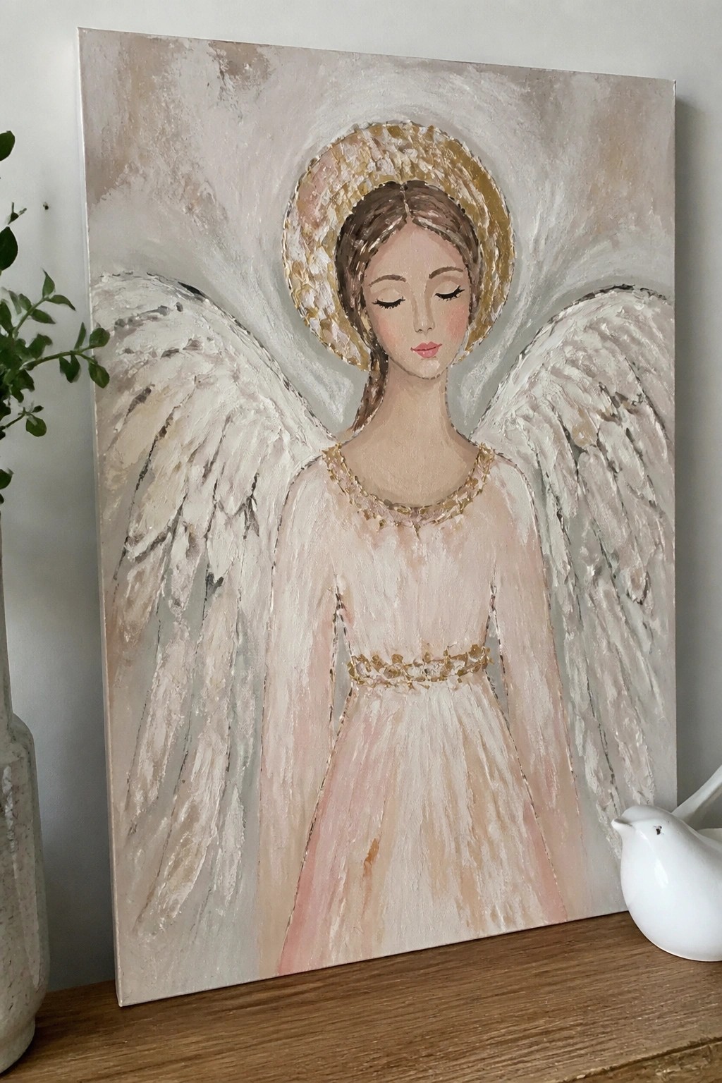 Angel painting of serene woman with golden halo, white wings, and pink dress