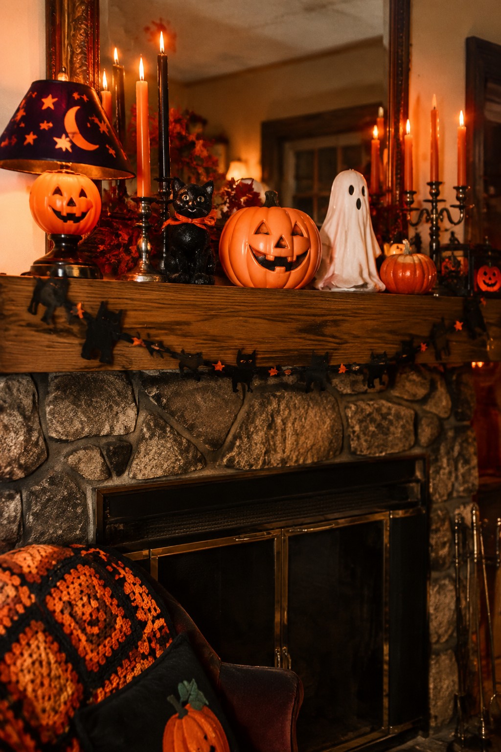 Halloween mantel with carved pumpkins, ghost, black cats, candles over stone fireplace