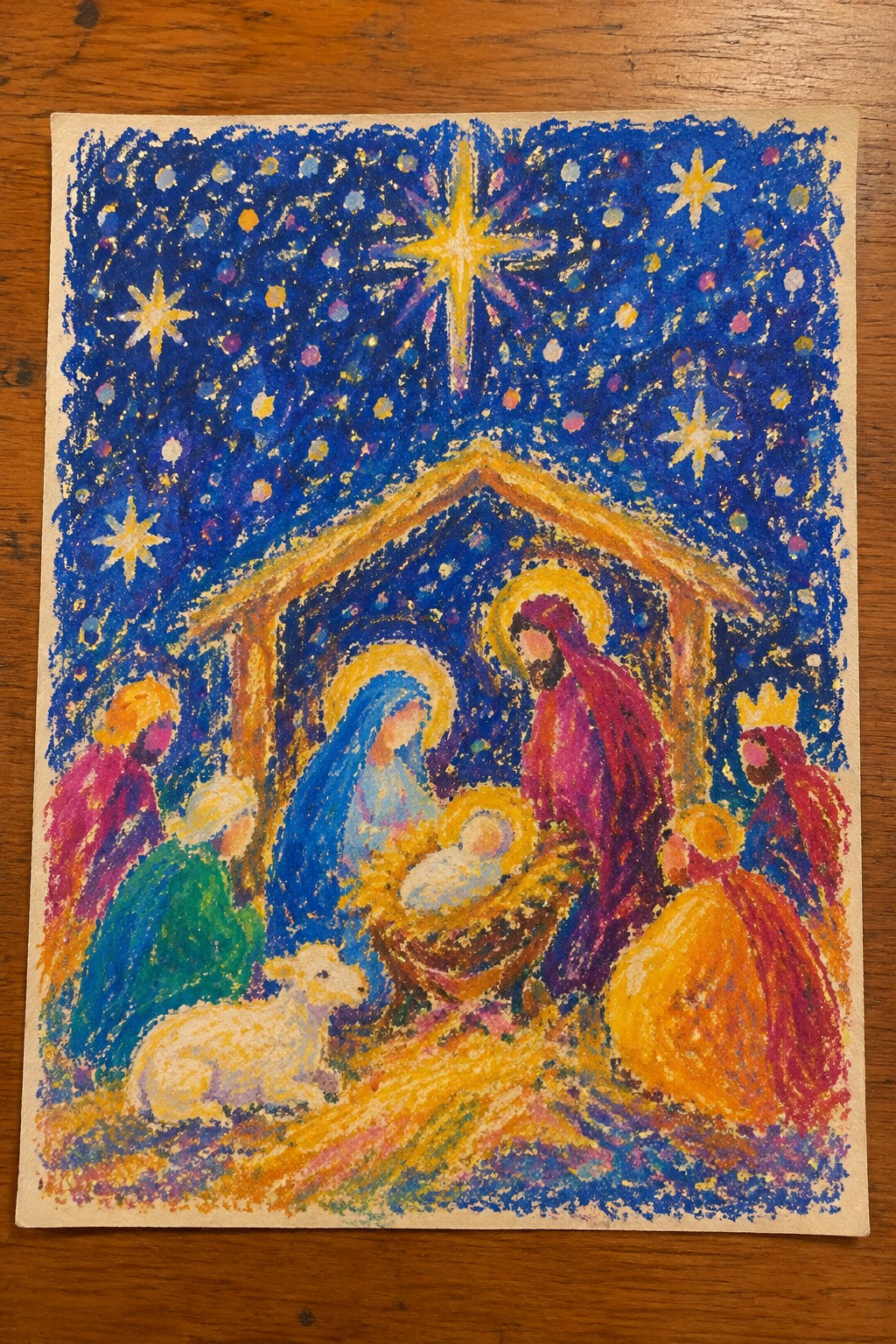 Colorful crayon nativity with robed figures, manger, lamb, and glowing star in starry sky.