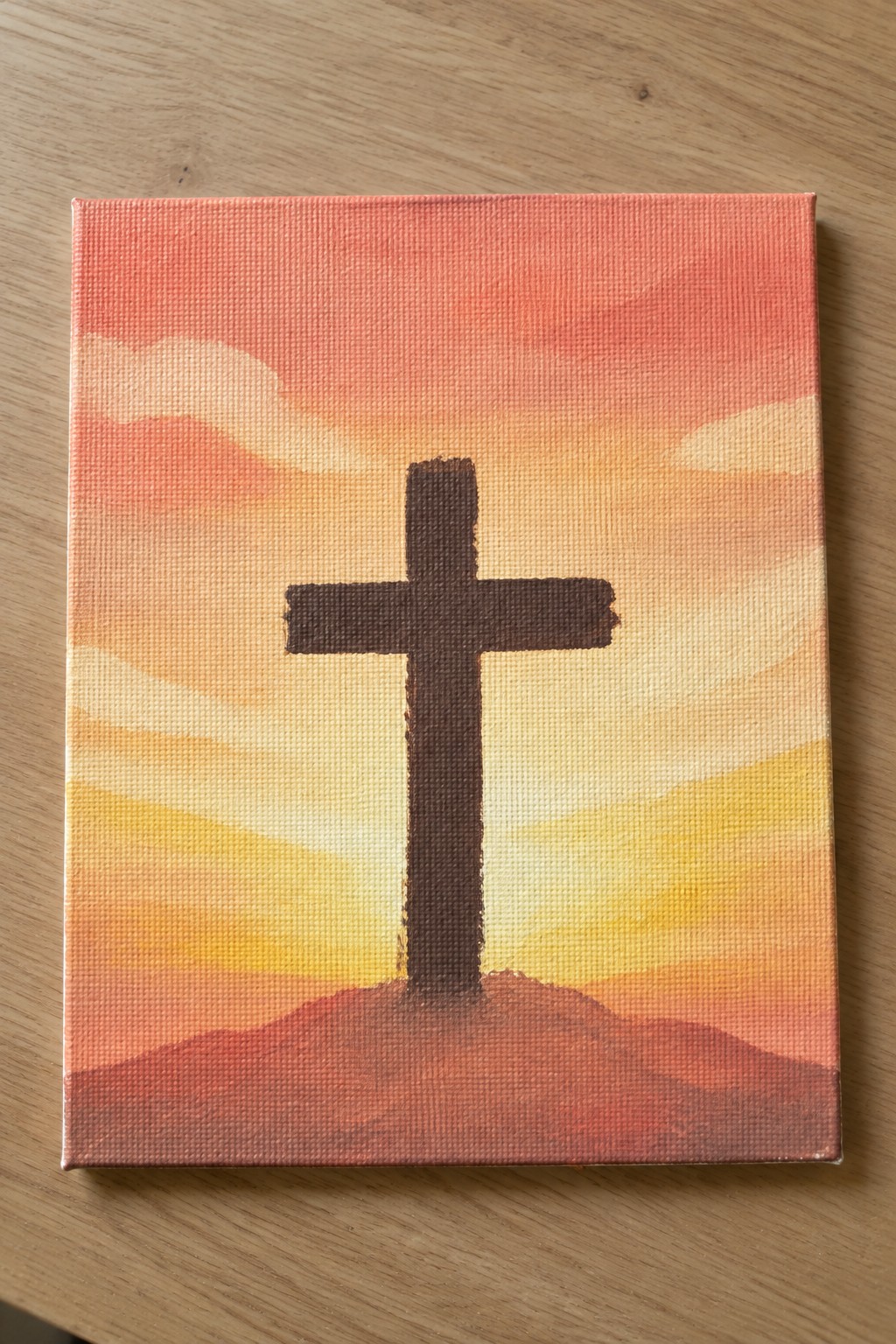 Brown cross on red hill against pink-orange sunset sky on canvas