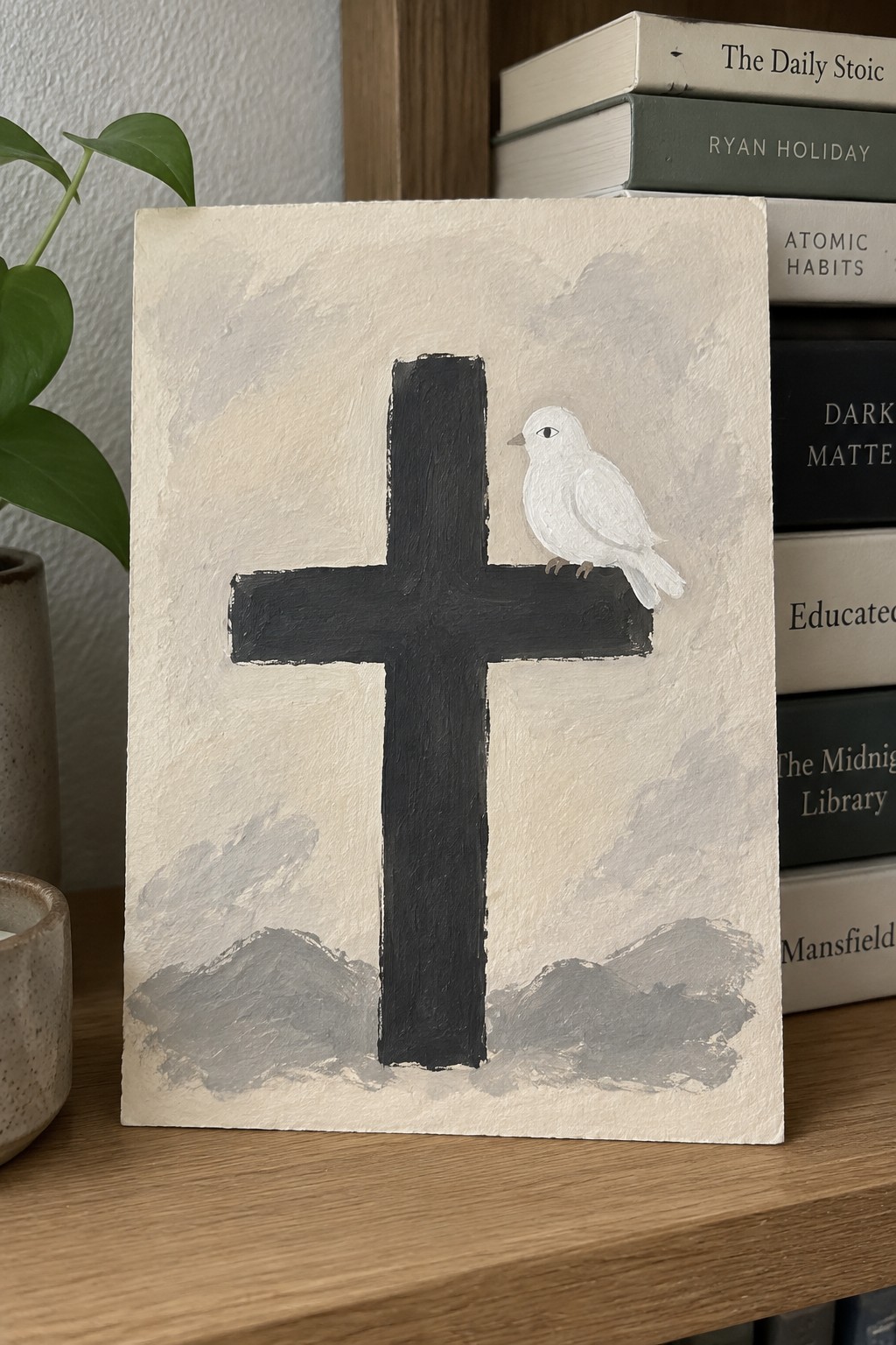 Black cross with white bird on arm, painted on textured beige canvas near books.