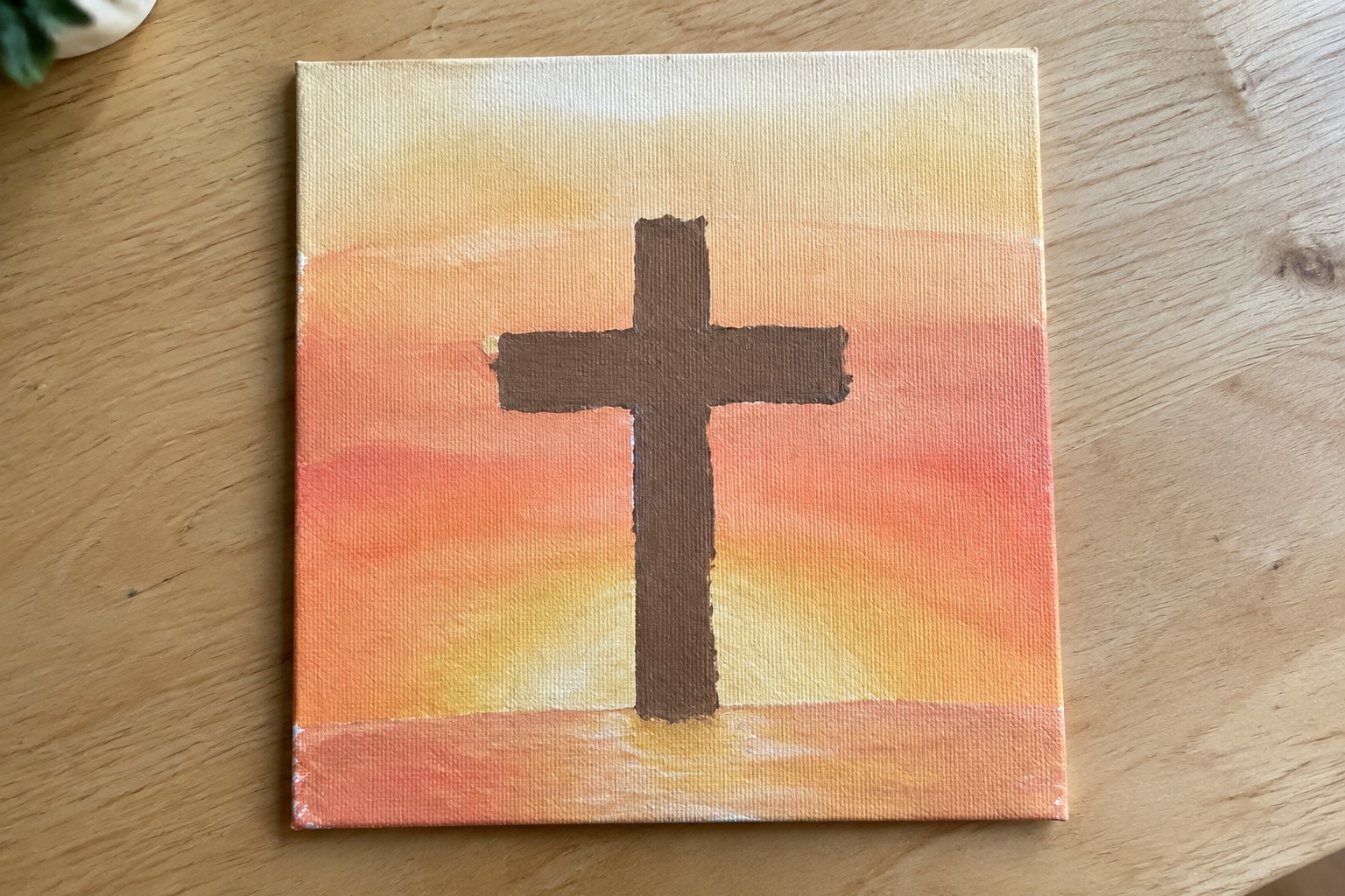 Brown cross on red hill against pink-orange sunset sky on canvas