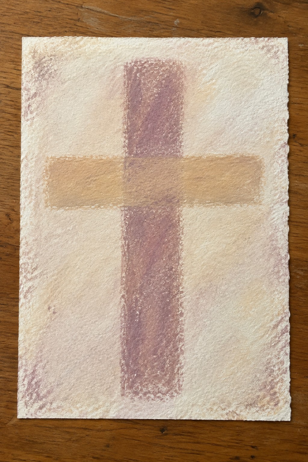 Textured paper cross with purple vertical and tan horizontal bars on wood.