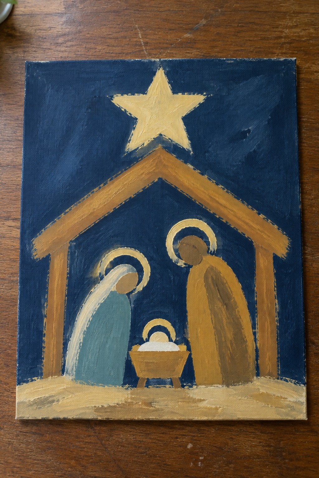 Nativity painting with blue-robed Mary, brown-robed Joseph, and haloed infant under golden star.