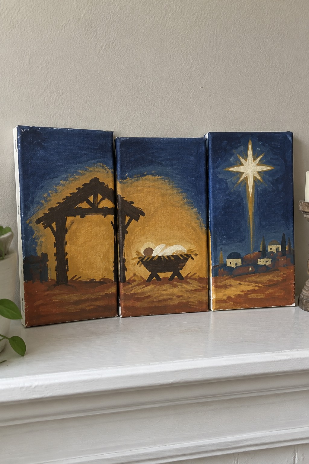 Three canvases depicting nativity stable, manger with infant, and star over town