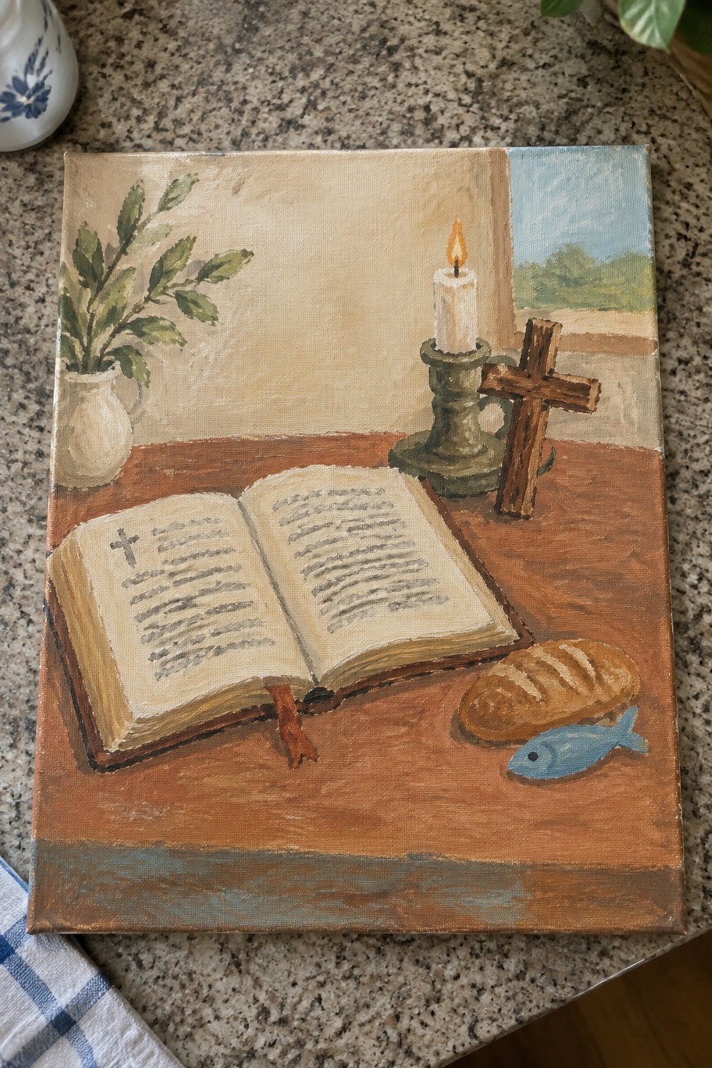 Still life painting of open book, lit candle, cross, bread, and blue fish on table